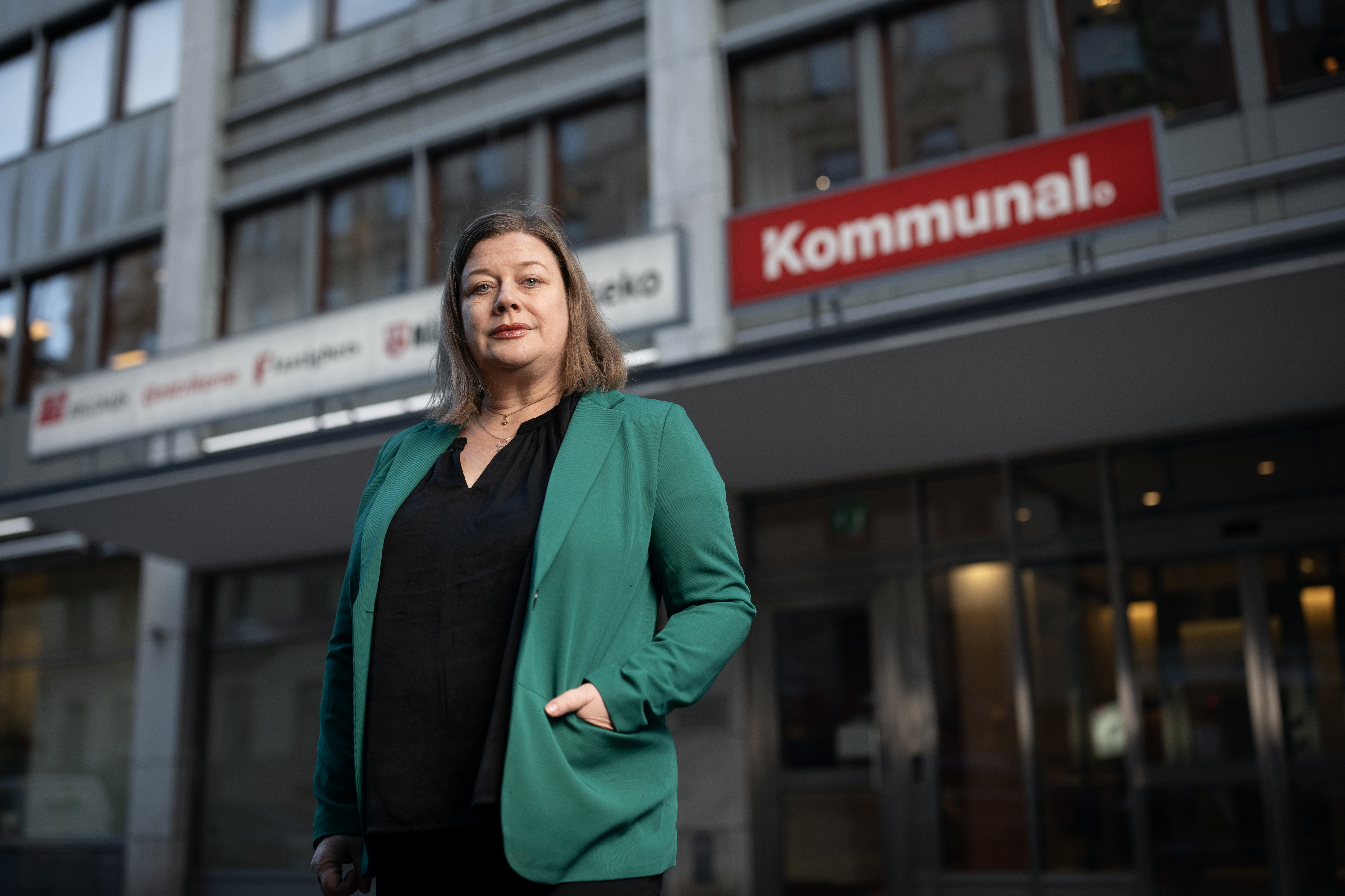 Malin Ragnegård i kavaj står framför Kommunals förbundskontor där det står ”Kommunal”.
