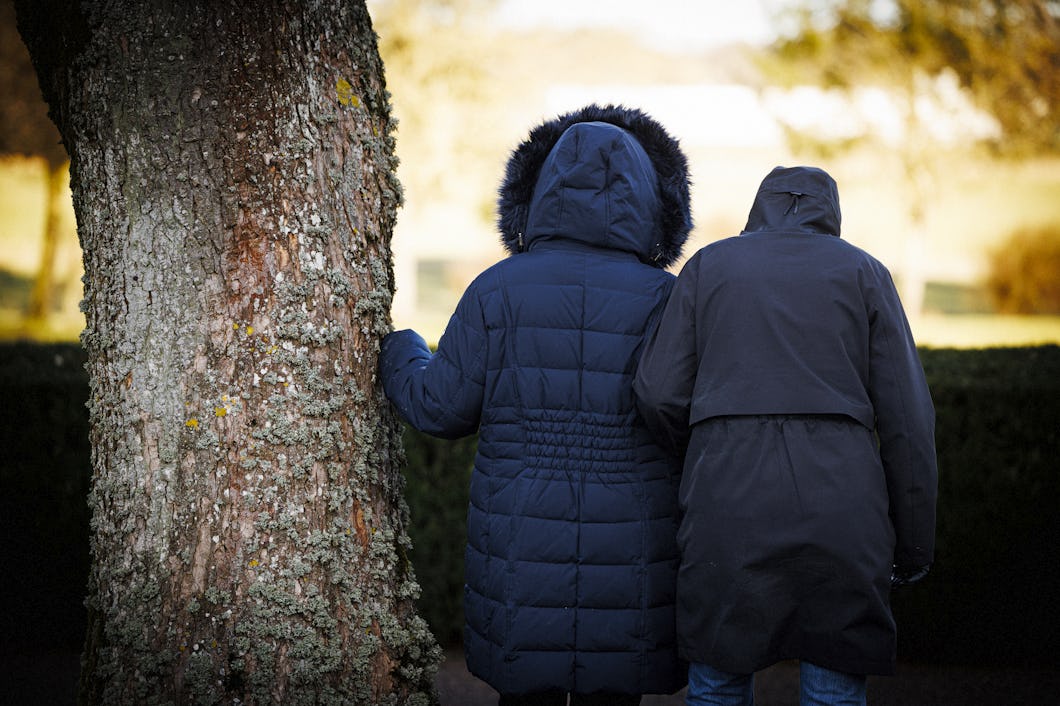 ”Maria” och ”Teresa” står tätt intill varandra vid ett träd som är täckt av mossa, vända bort.