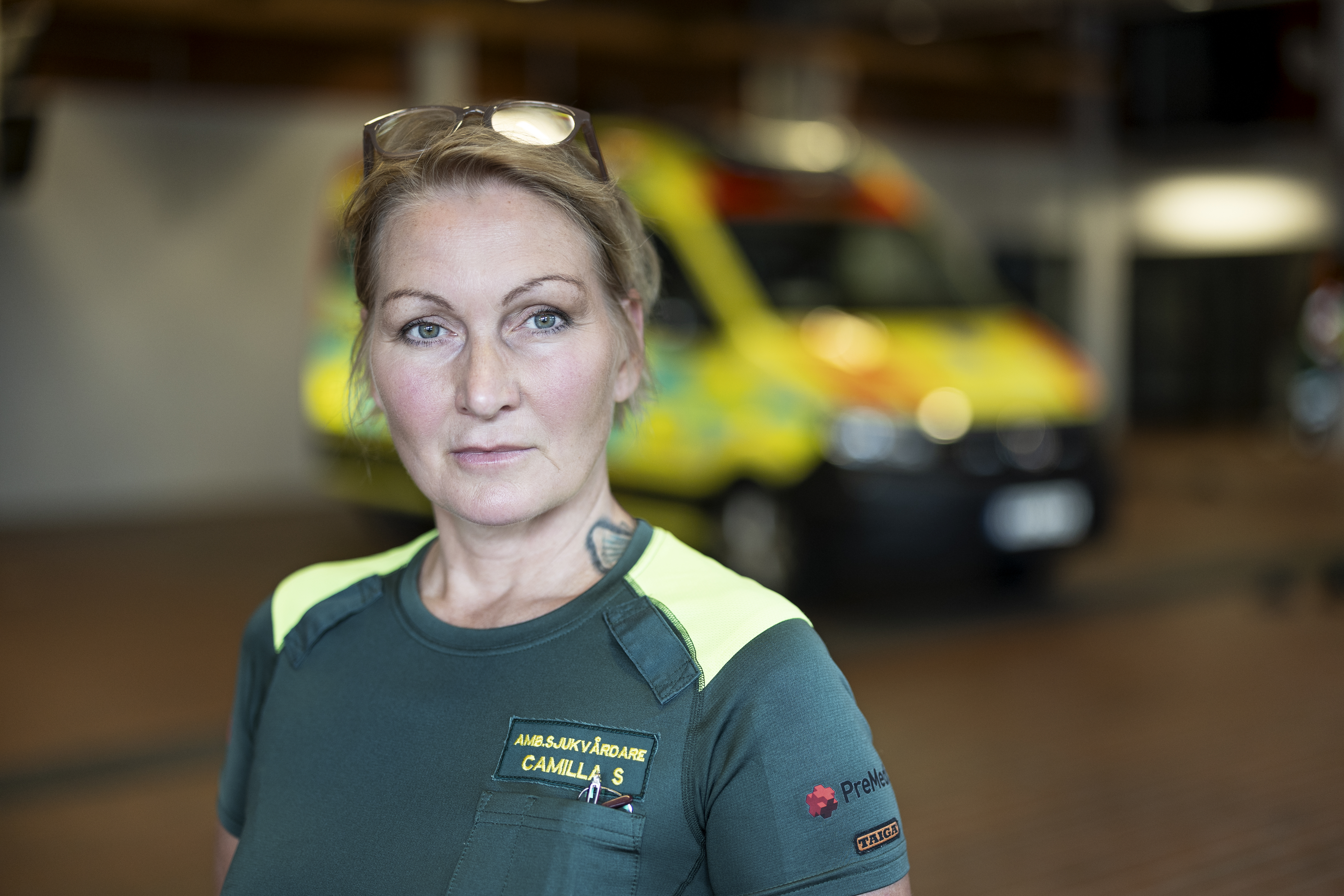 Camilla Sorbey står inomhus, med en otydlig ambulans synlig i bakgrunden.