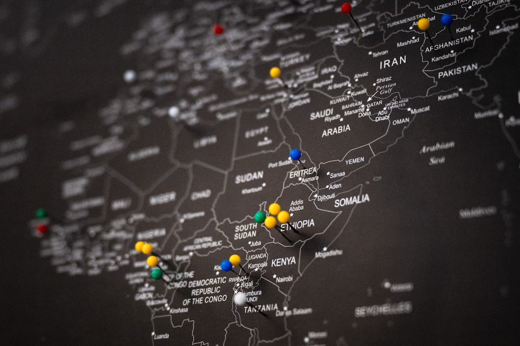 En världskarta med ländernas namn synliga, markerad med färgade nålar i Afrika som visar olika platser i länder som Etiopien och Tanzania.