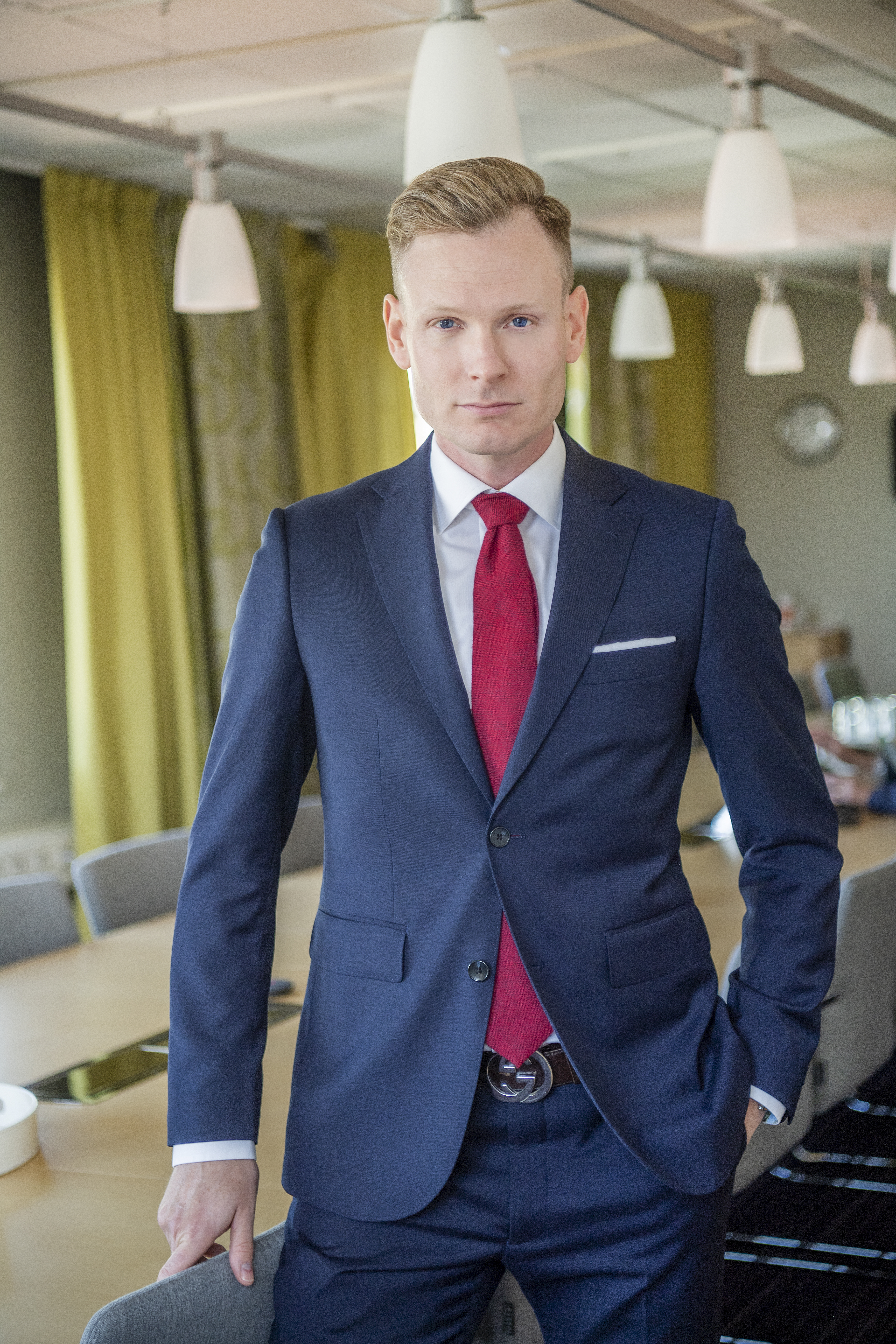 Torbjörn Granevärn i mörkblå kostym med röd slips står i ett konferensrum med gröna gardiner och hängande lampor.