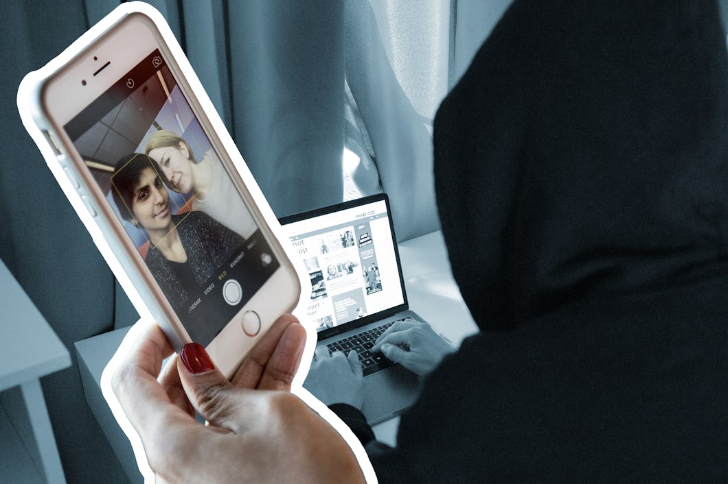 En person med huva använder en bärbar dator medan någon annan håller upp en mobiltelefon som visar en selfie av två personer.