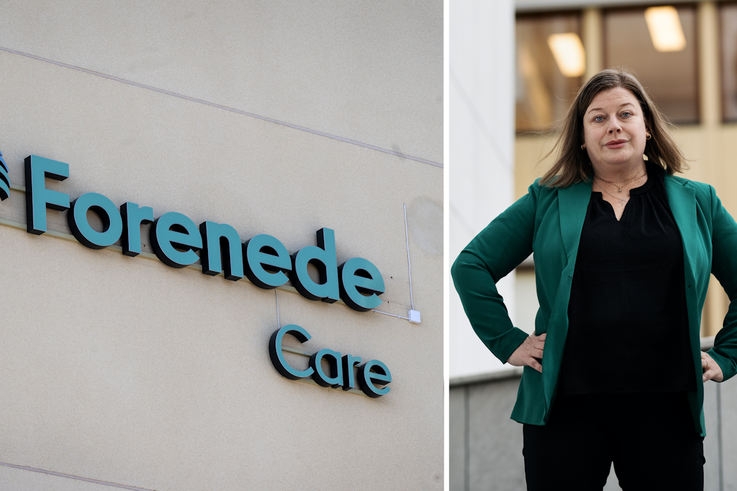 En skylt med texten "Forenede Care" sitter på en vägg. Bredvid står en kvinna i grön kavaj med händerna på höfterna.