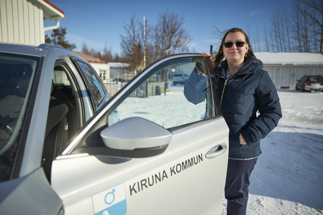 Mandy Heinemann med solglasögon och vinterjacka står bredvid en bil med logotypen ”Kiruna kommun” utomhus i snö.