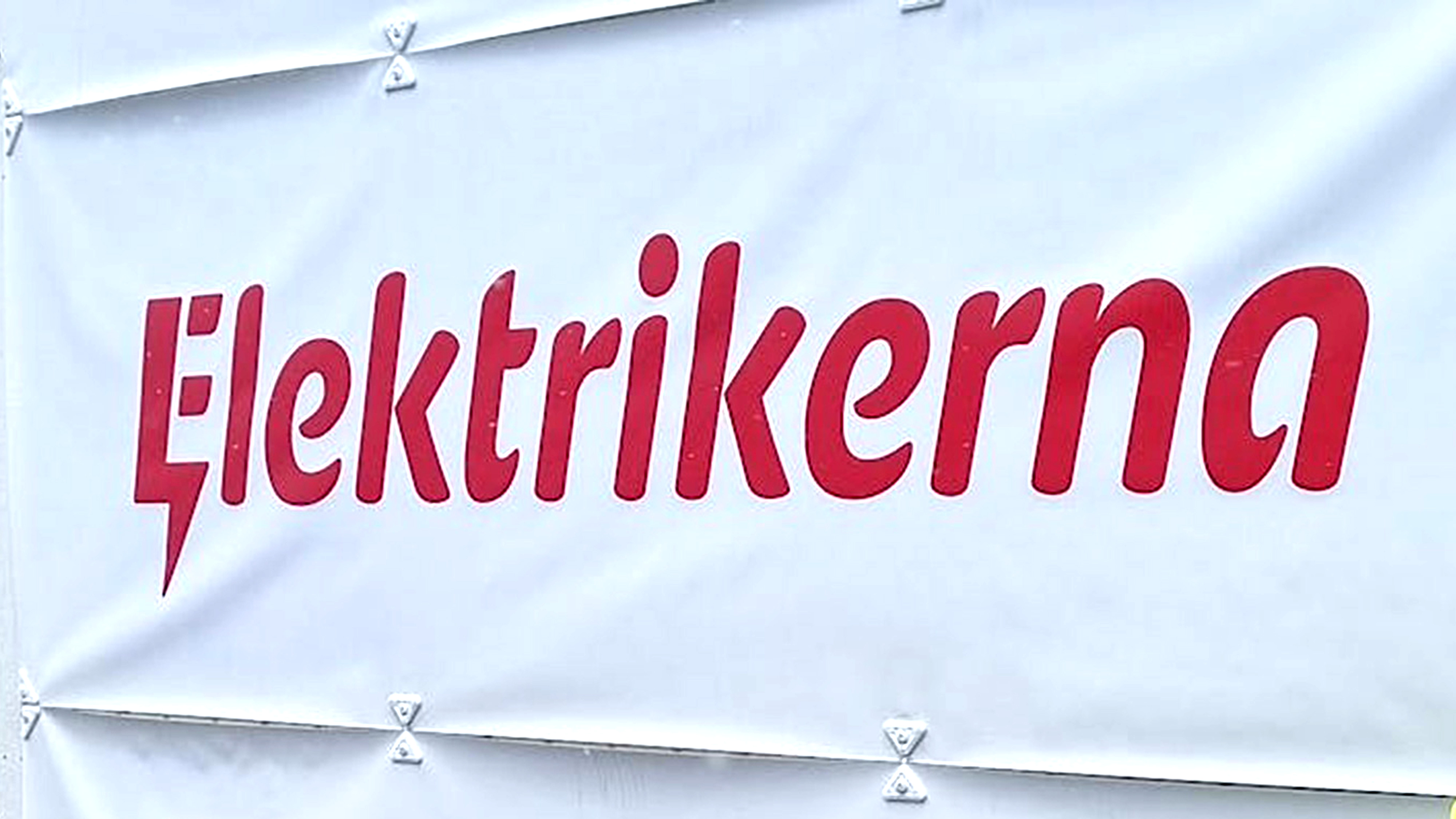 Vit banderoll med ordet "Elektrikerna" i röd text, där den inledande bokstaven "E" är utformad för att likna en blixt.