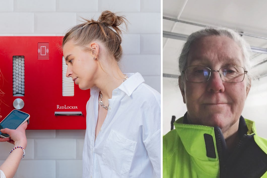 Två kvinnor använder en smartphone framför en röd varuautomat; till höger står en äldre person med glasögon och grön jacka vänd mot kameran.