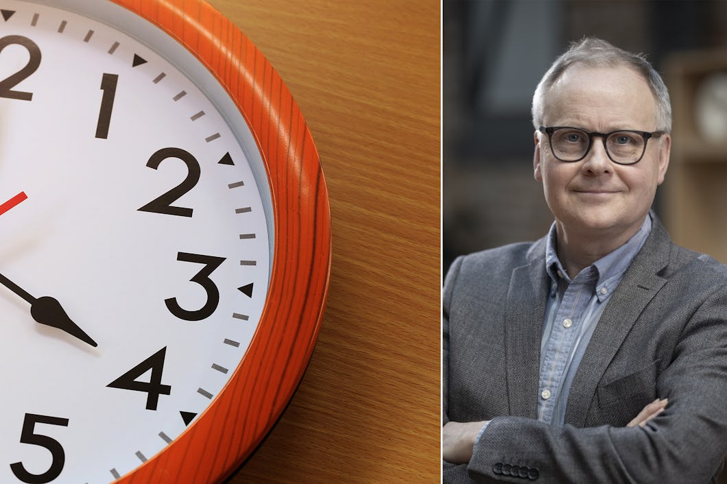 En väggklocka visar tiden 2:59. Bredvid stårPatrick Joyce med glasögon och kavaj, med armarna i kors, som tittar in i kameran och ler.