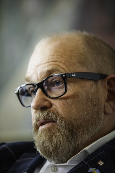 Johan Lindholm med svarta Ray-Ban-glasögon och kavaj tittar åt sidan med allvarlig min.