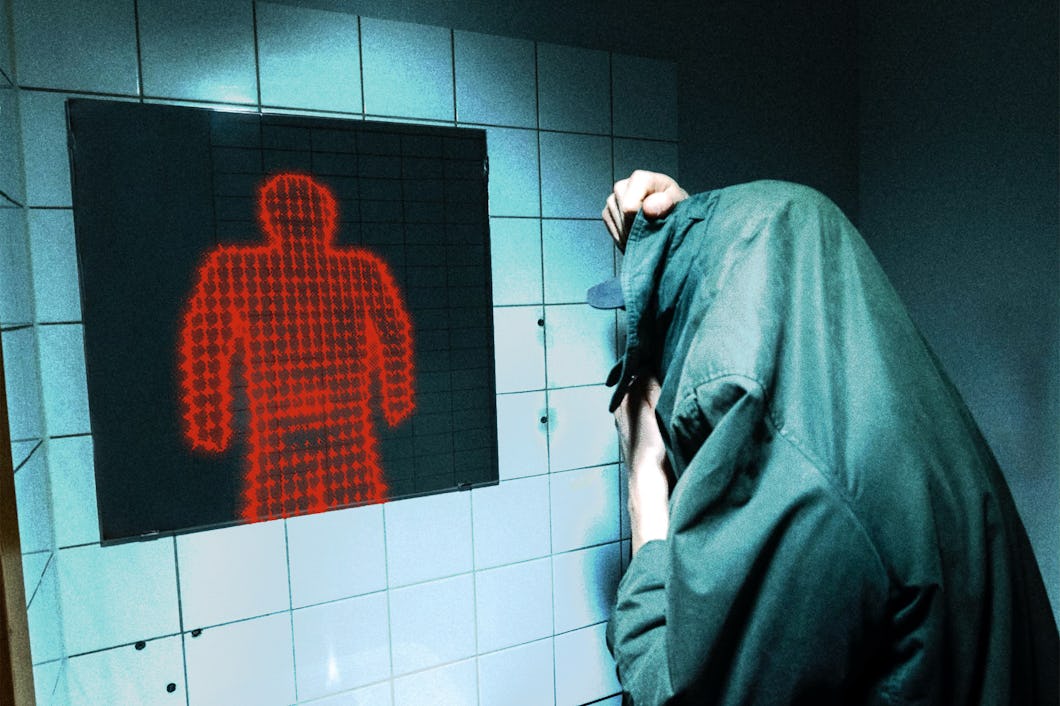 En person med en jacka över huvudet står vid ett handfat och tittar i en spegel som visar en röd mänsklig figur gjord av digitala punkter.