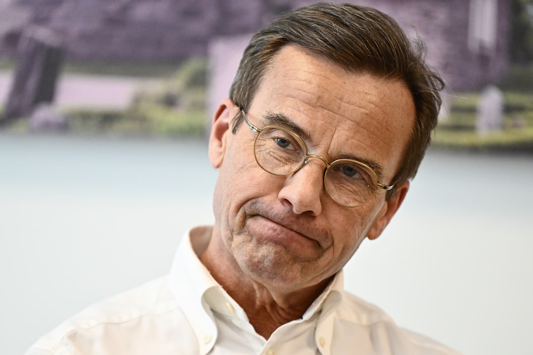 En man i medelåldern med glasögon och vit skjorta tittar nedåt.