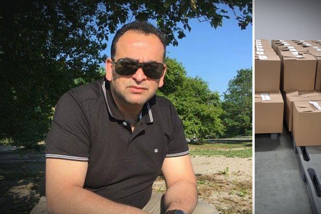 En man med solglasögon sitter utomhus; bredvid honom står staplar med förslutna kartonger på pallar inomhus.