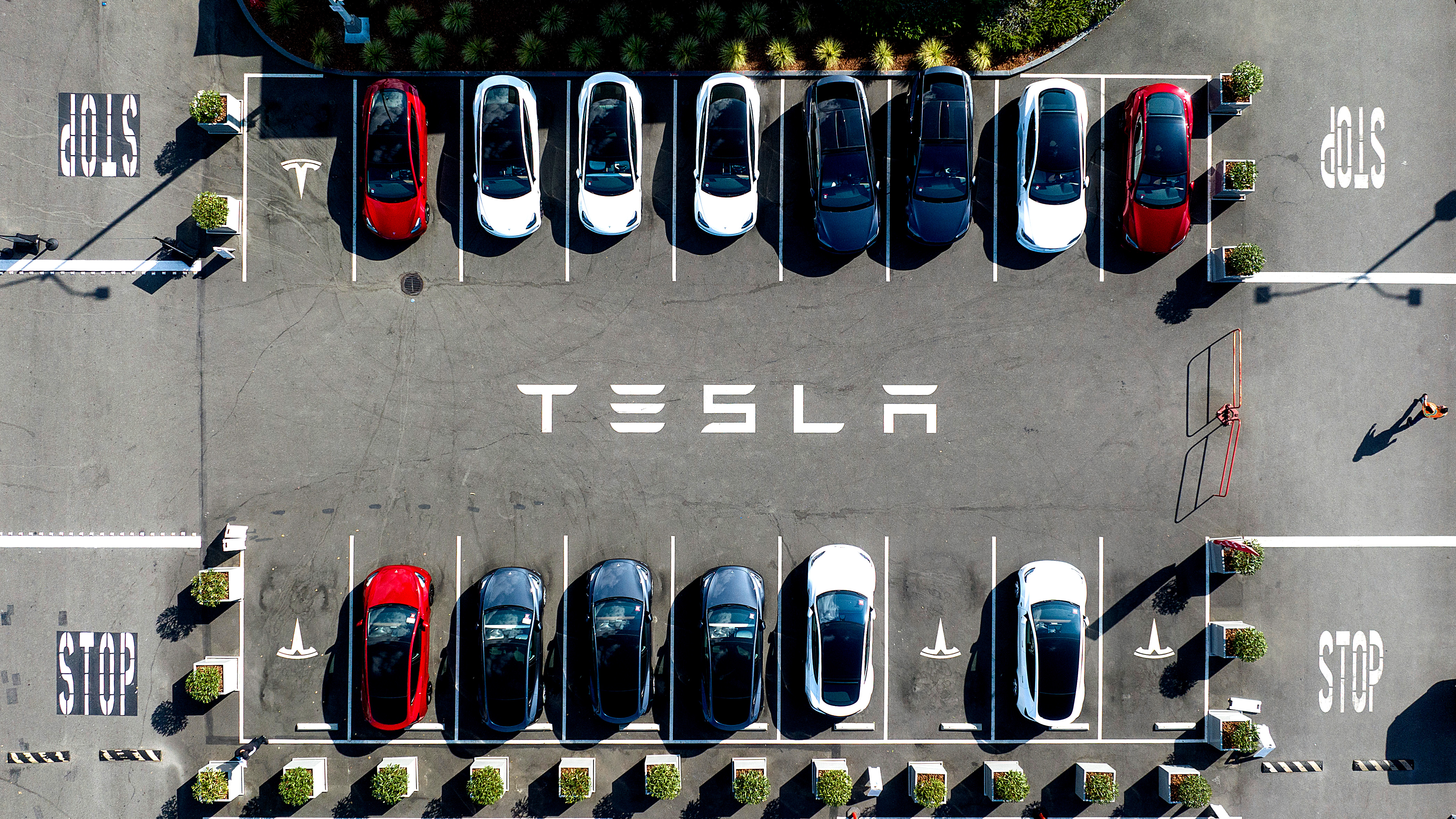 Flygfoto över en parkeringsplats med Tesla-märkta platser, där flera Tesla-bilar står parkerade.