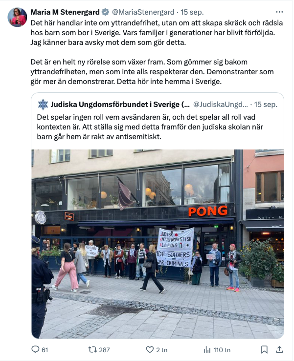 En grupp människor håller en banderoll och israeliska flaggor utanför en butik i stadsmiljö. Andra står bredvid och tittar på. Texter på banderollen nämner judiska ungdomar på svenska.