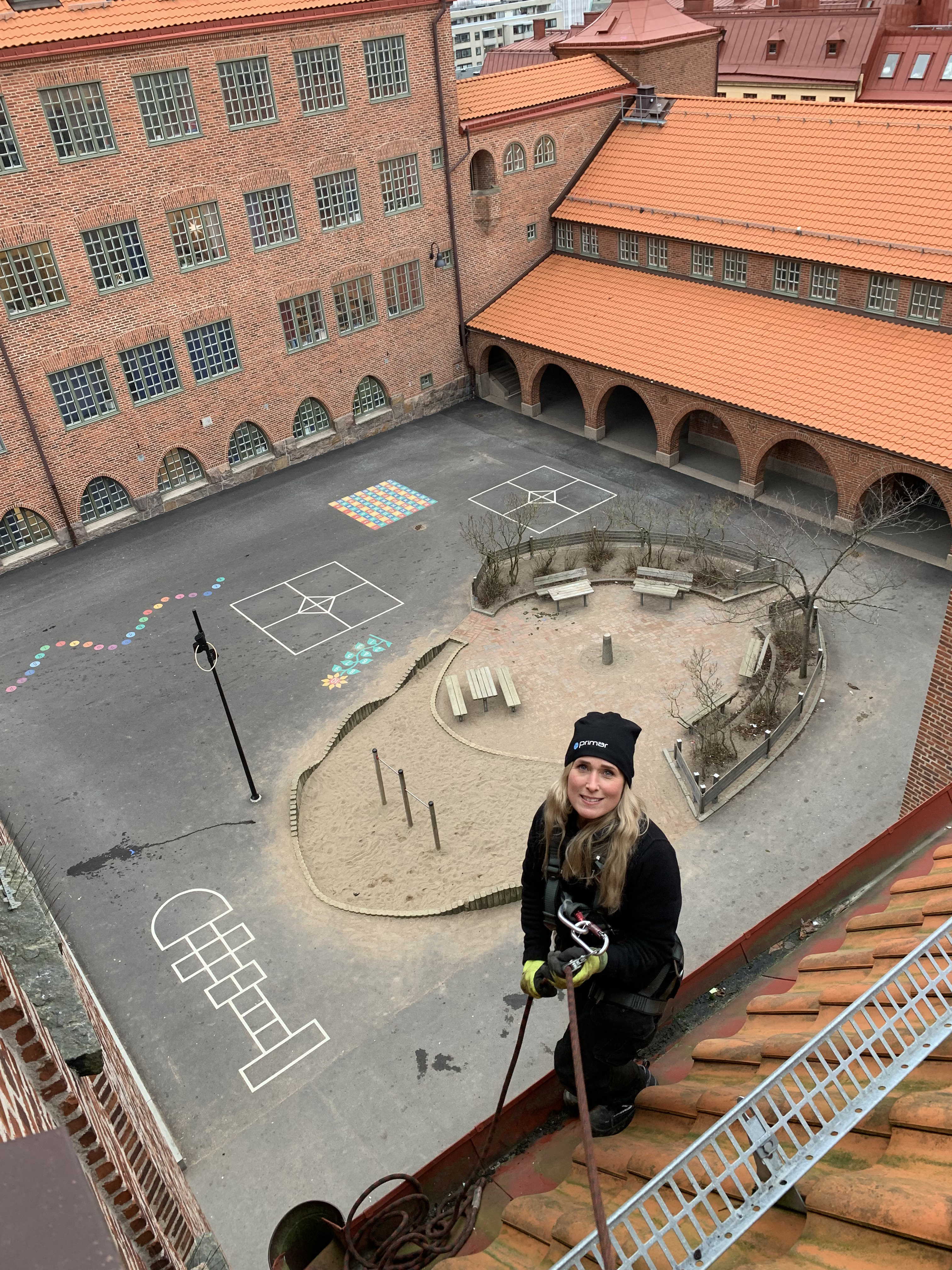 Therése Svedberg på ett högt tak ovanför en skolgård