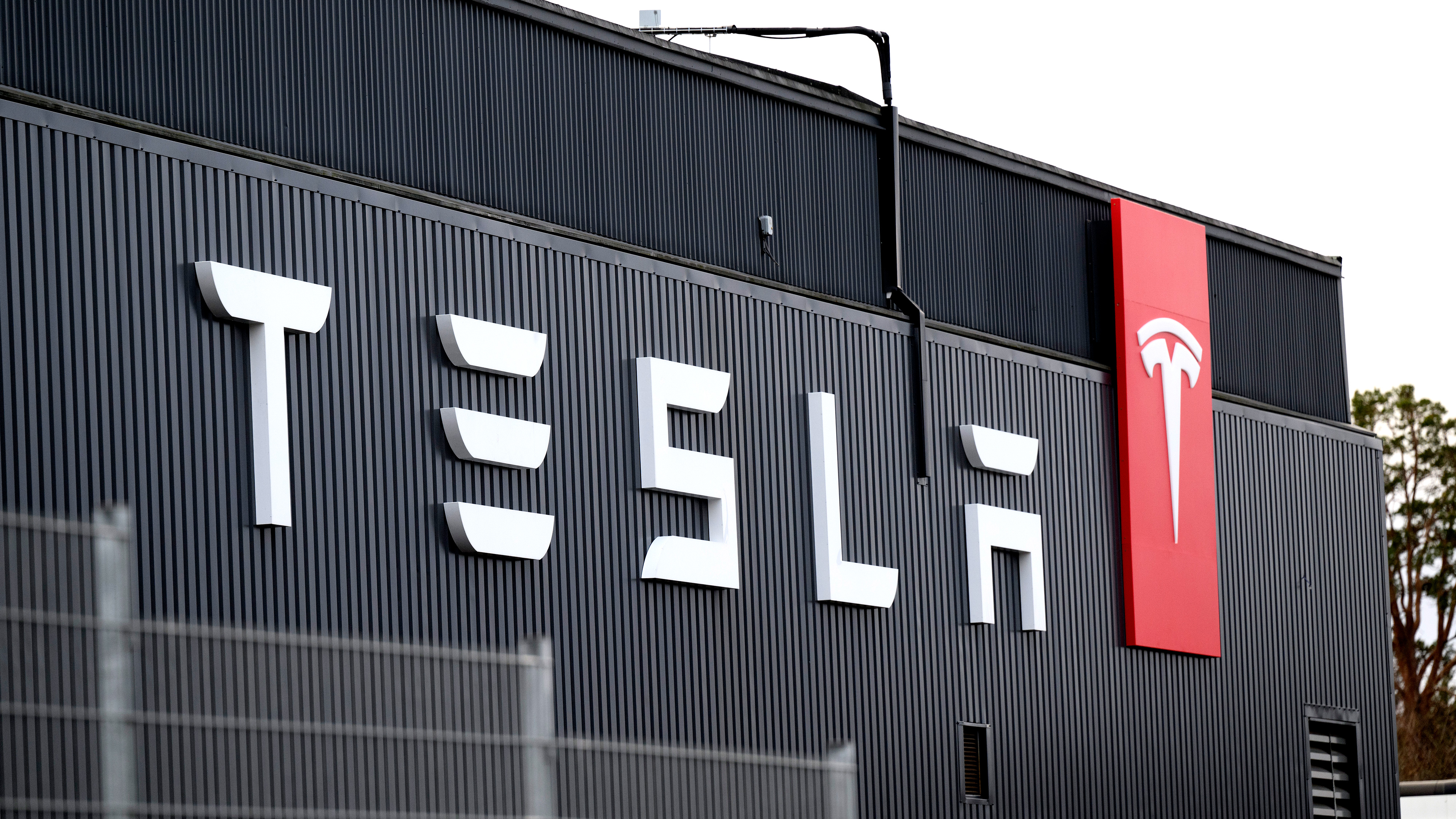 Byggnadens utsida med Teslas logotyp och namn på en vägg av svart korrugerad plåt.