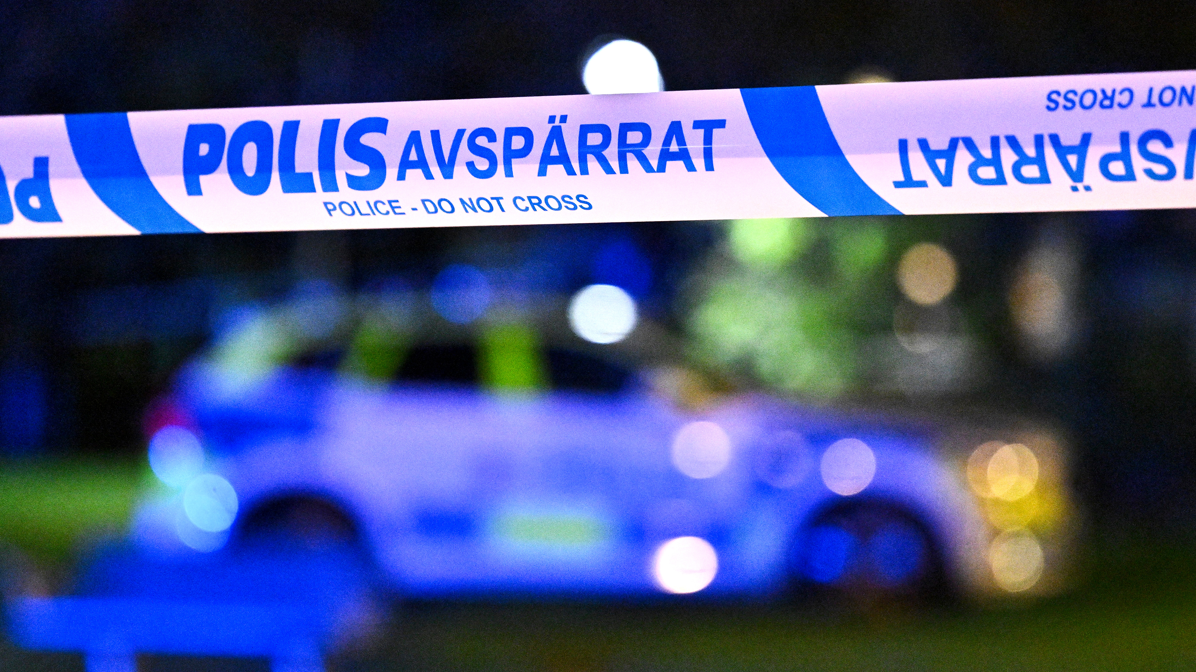 En avspärrning med bandet "POLIS AVSPÄRRAT" och en polisbil syns i bakgrunden på natten.