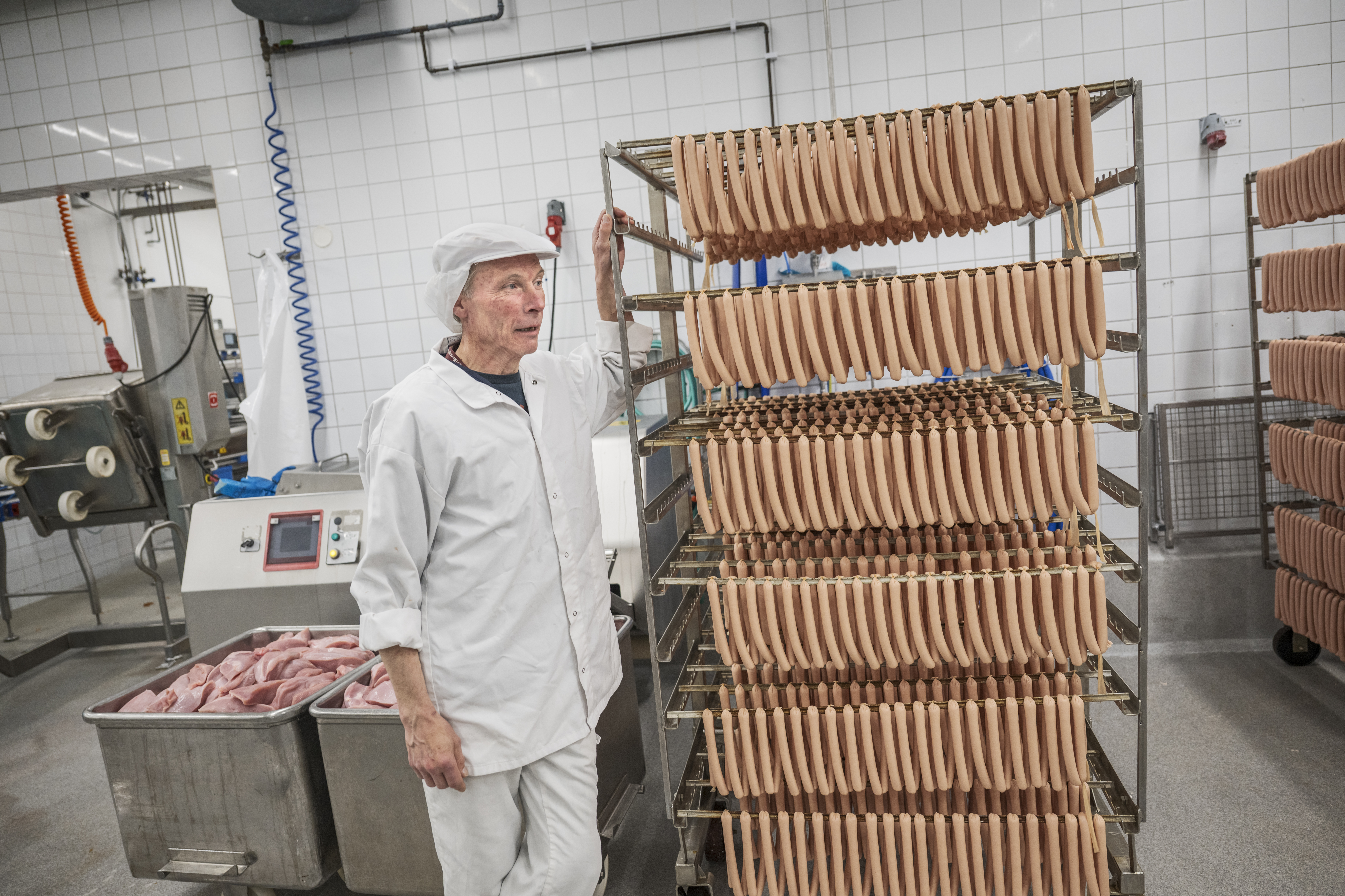 Mikael Olsson i arbetskläder bredvid en ställning med korvar.