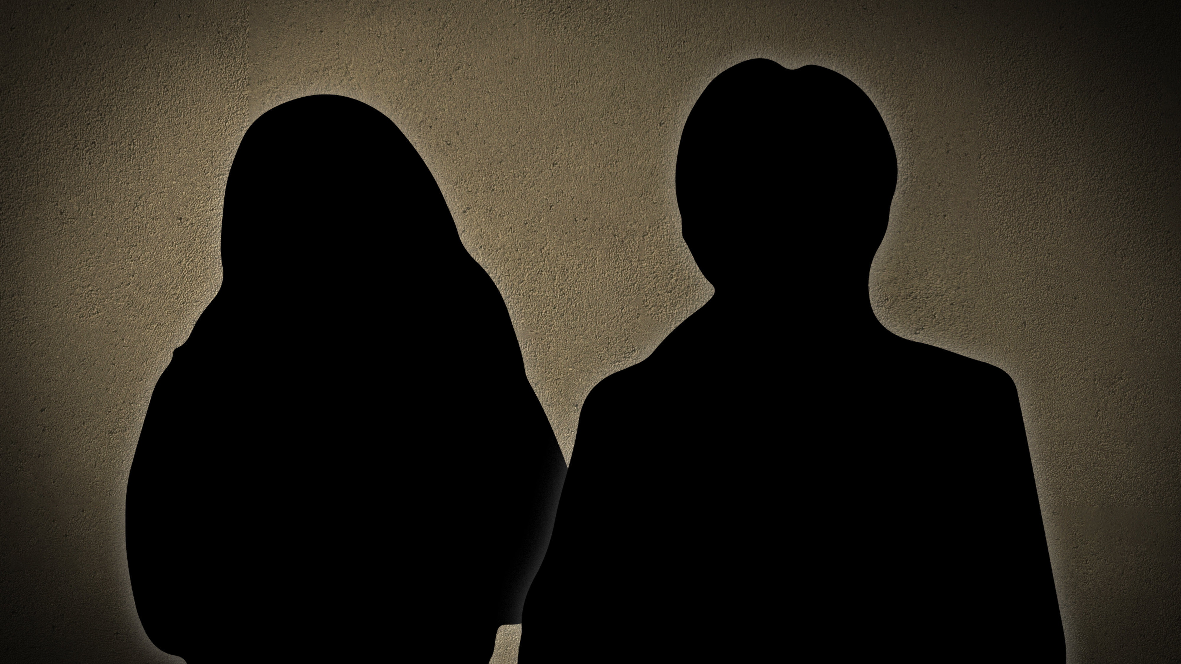 Två personer står bredvid varandra framför en enkel bakgrund med struktur.