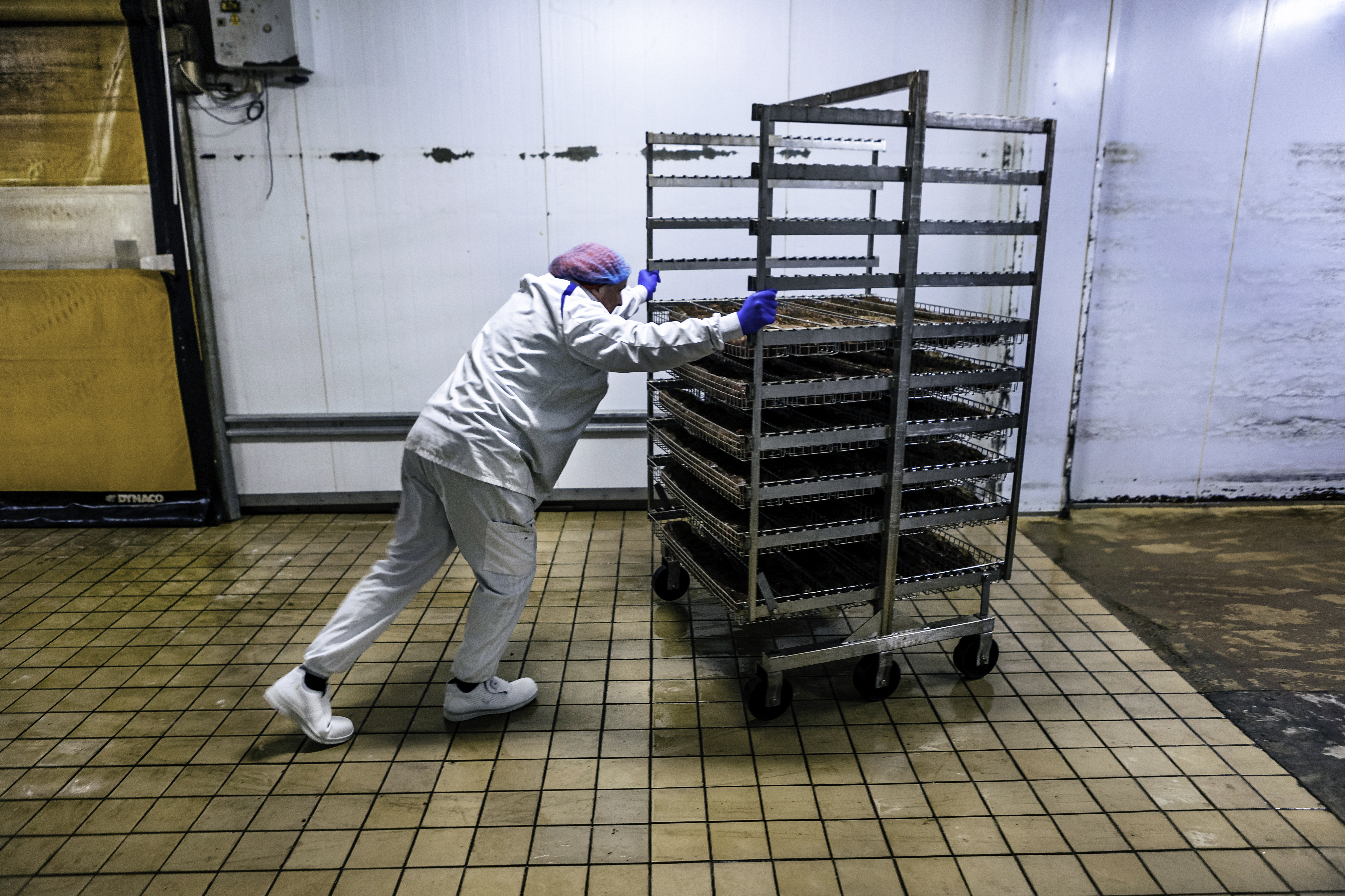 Micael Andersson flyttar på en rullvagn med hyllor.