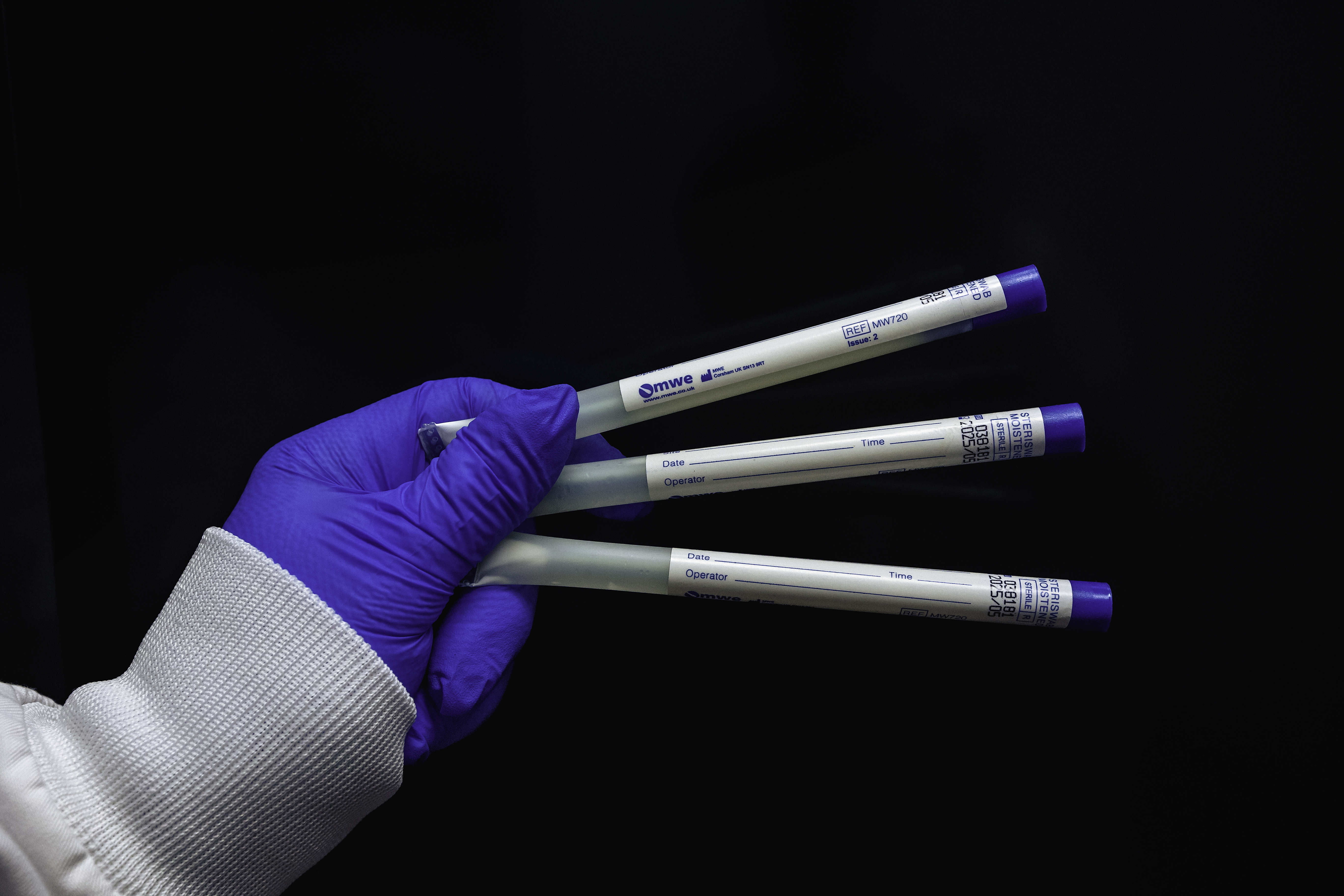 En hand som håller i tre provrör