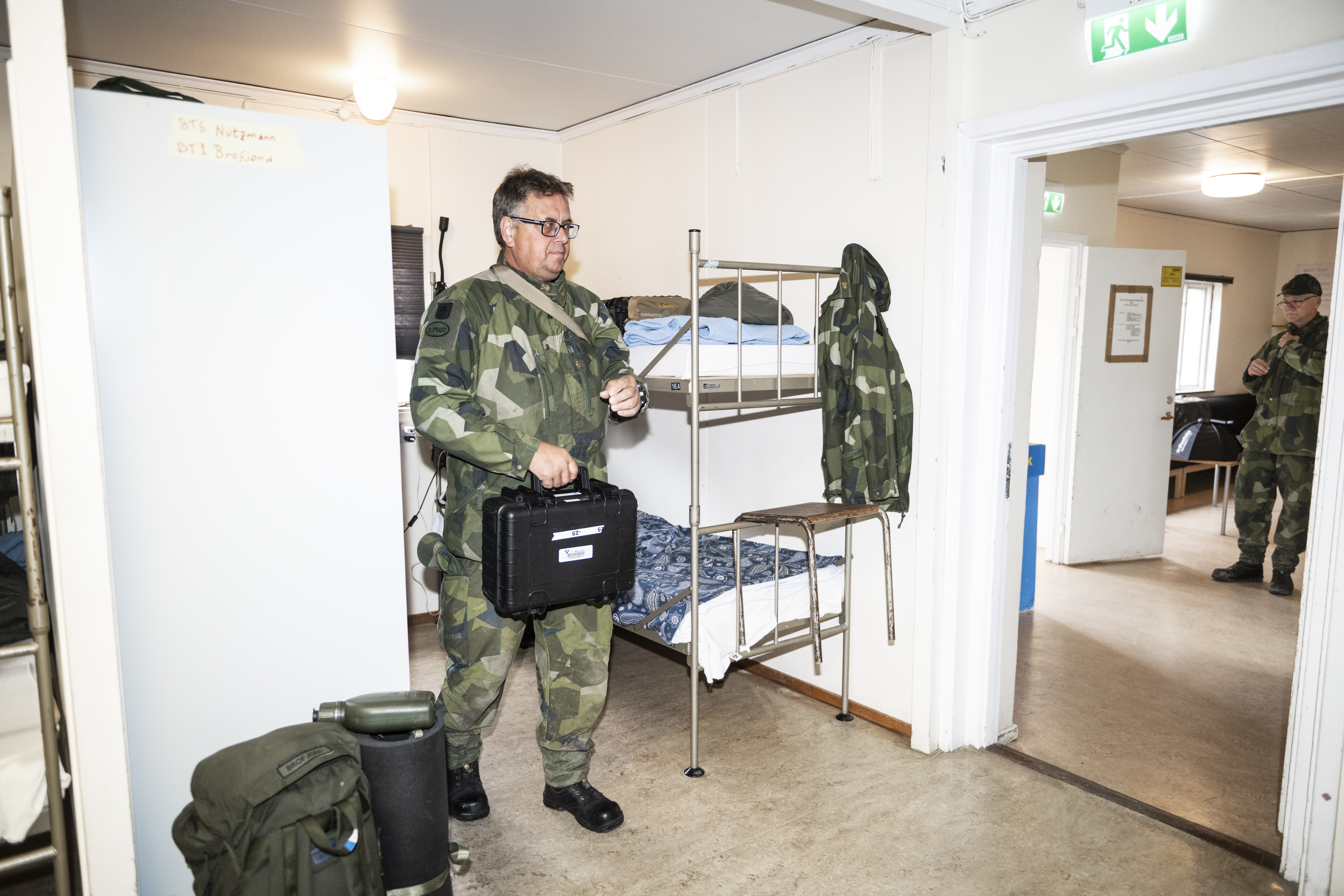 En person i militäruniform står i ett logement med våningssängar.