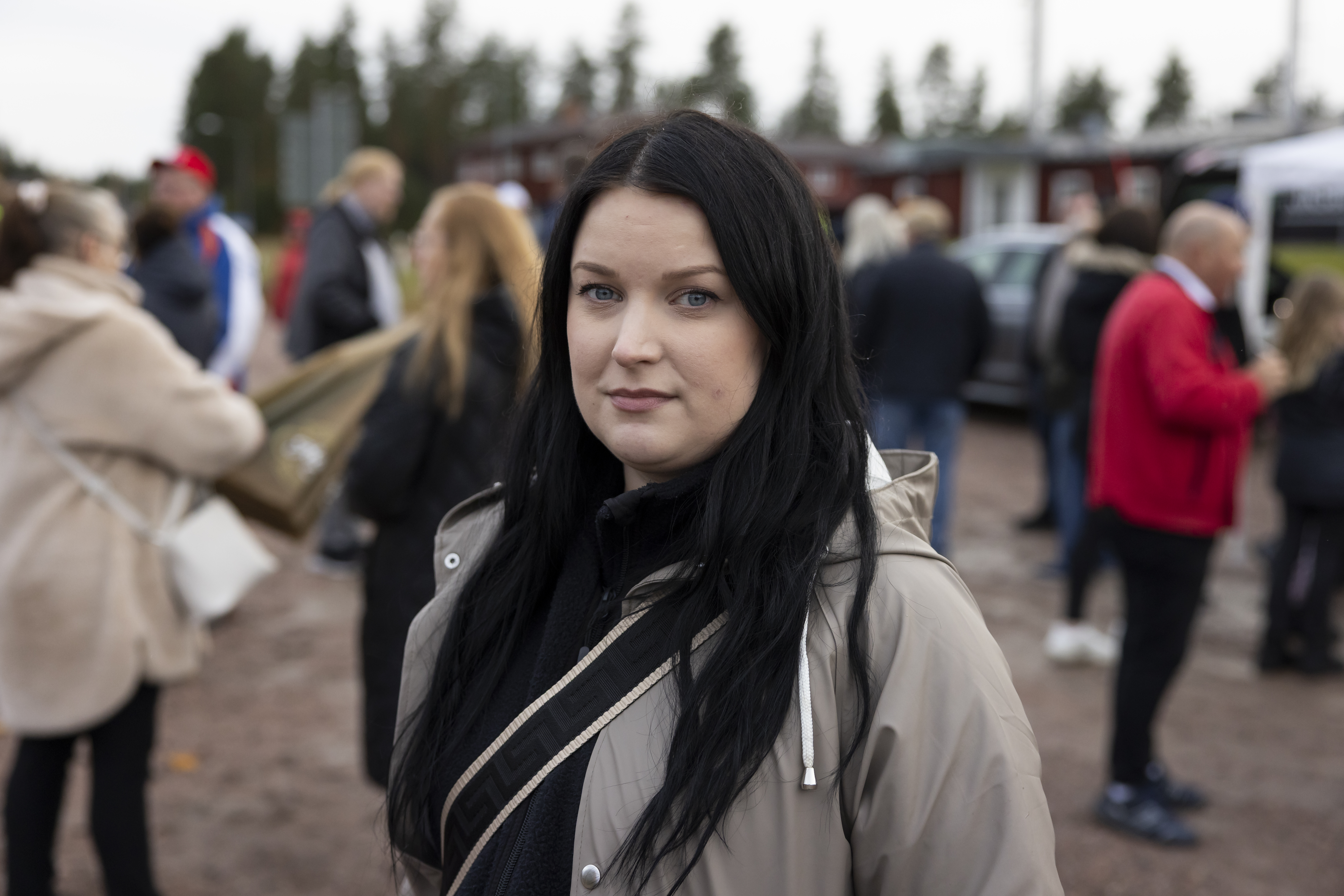 Mörkhårig kvinna med bege jacka.