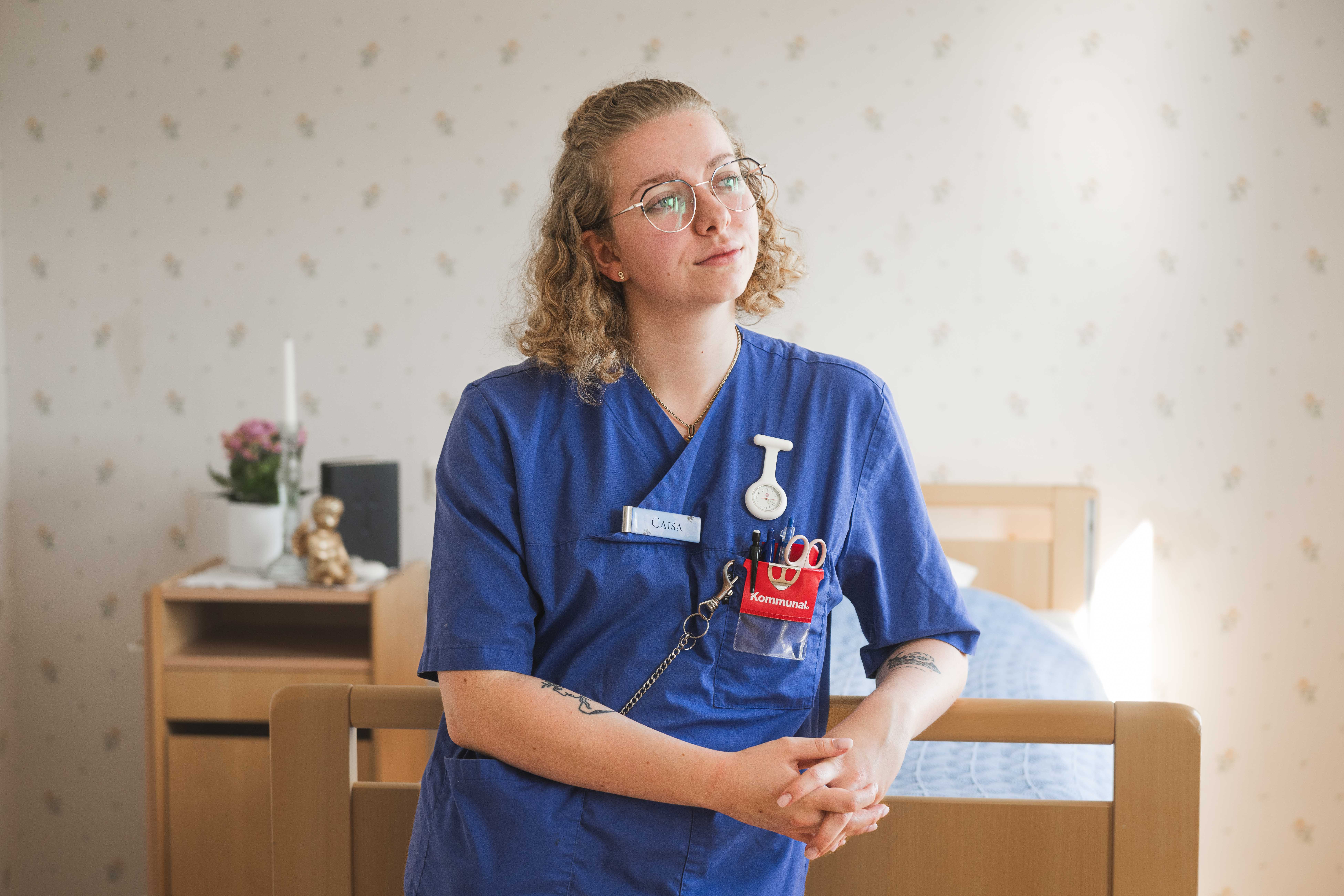 Bild på Caisa, vårdare, som står framför en säng.