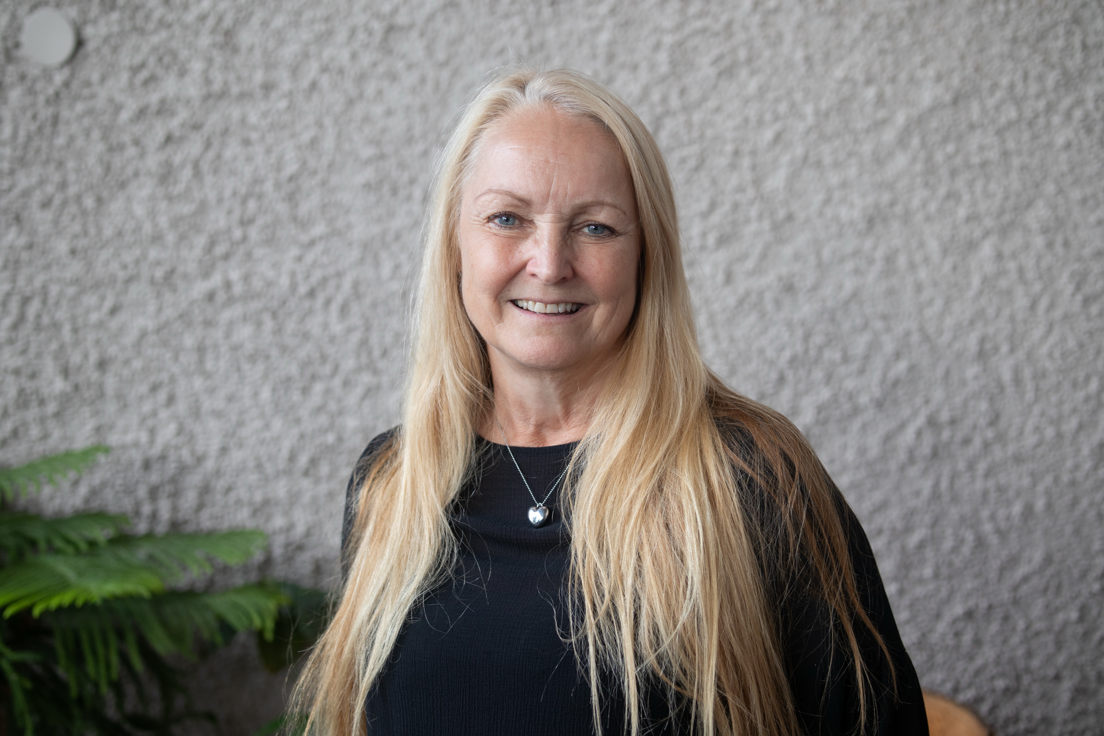 Kvinna i långt blont hår tittar i kameran.