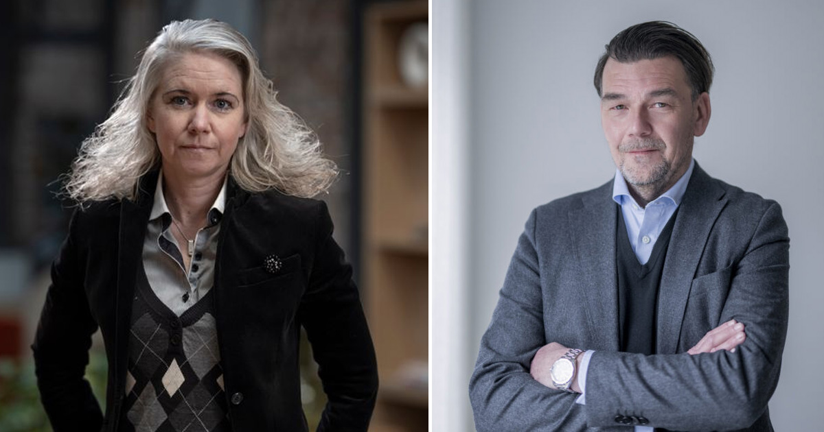 En kvinna med axellångt grått hår och svart kavaj står utomhus, medan en man med mörkt hår i grå kostym står inomhus med armarna i kors.