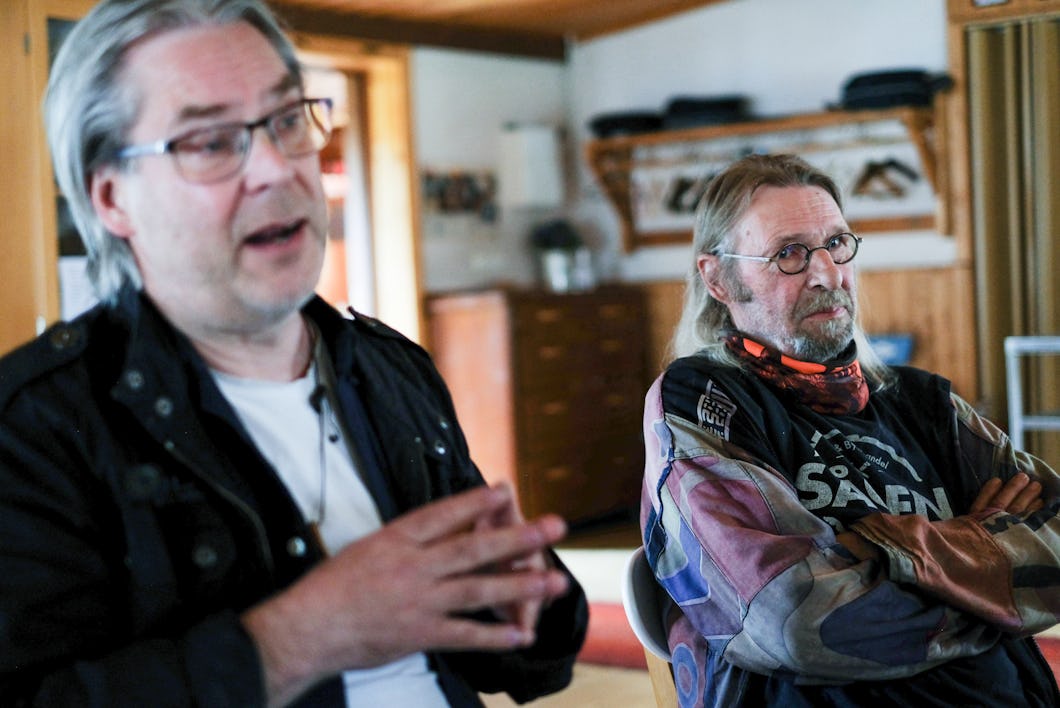 Mats Sidmalm och Ulrik Lidström sitter inomhus; Mats pratar och gestikulerar, Ulrik lyssnar med armarna i kors och har glasögon och jacka.