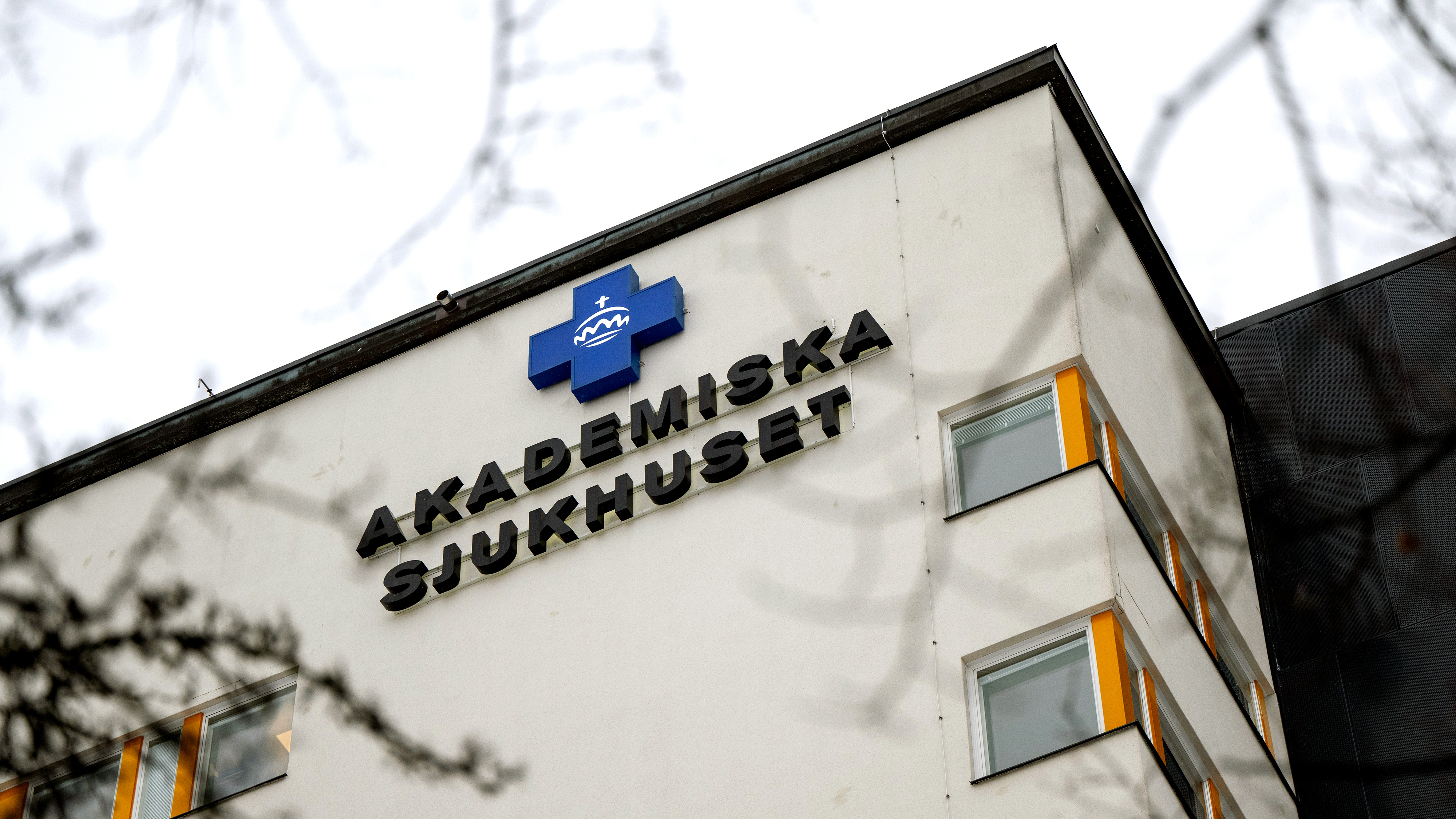 En sjukhusbyggnad med skylten "Akademiska Sjukhuset" och en blått kors-logotyp på ytterväggen.