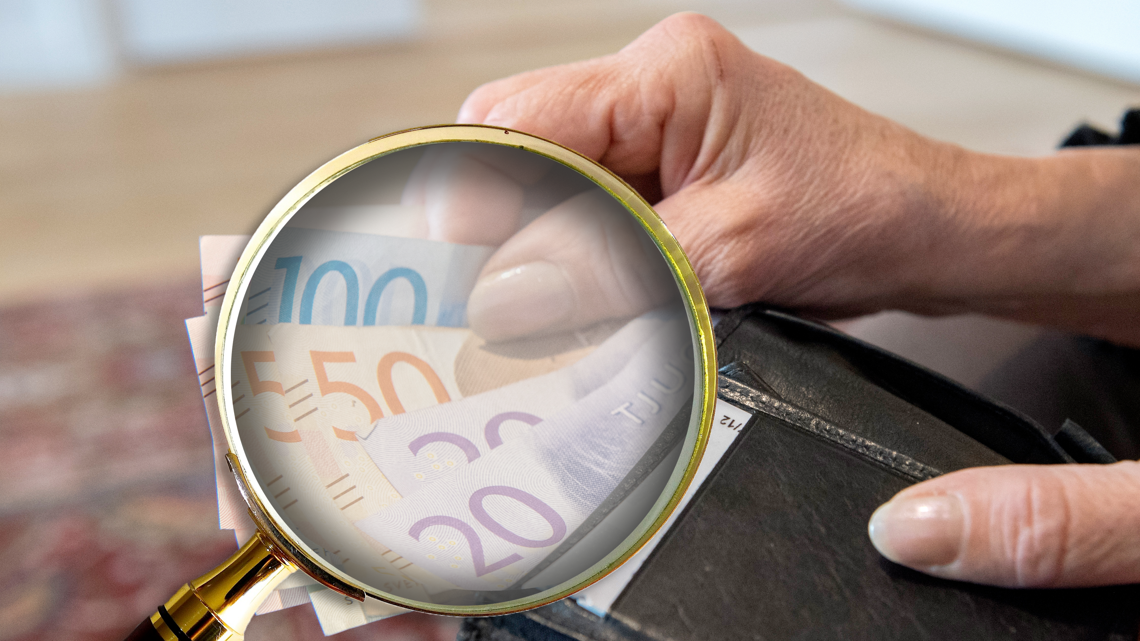 Ett förstoringsglas som zoomar in på sedlar i en plånbok.