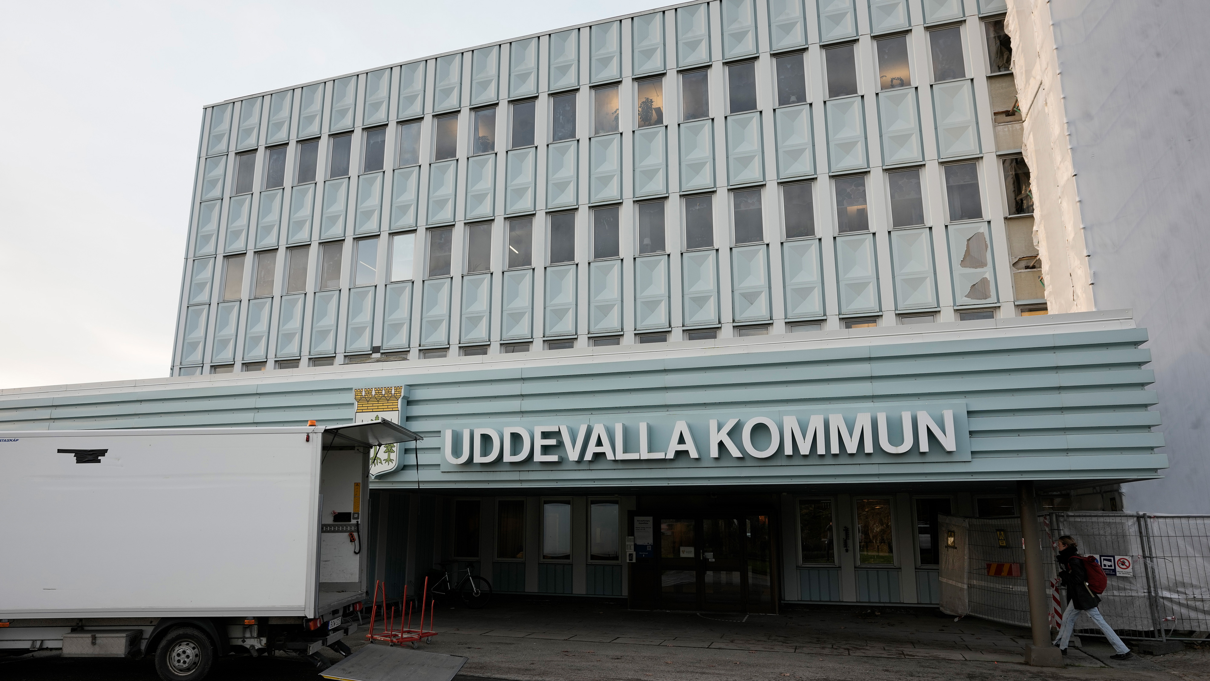 Entrén till en byggnad med skylten "UDDEVALLA KOMMUN" ovanför, framför står en vit lastbil parkerad.