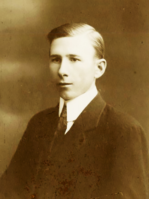 En ung Clas Ohlson i kostym och slips poserar för ett sepiafärgat porträtt med neutral min mot en enkel bakgrund.