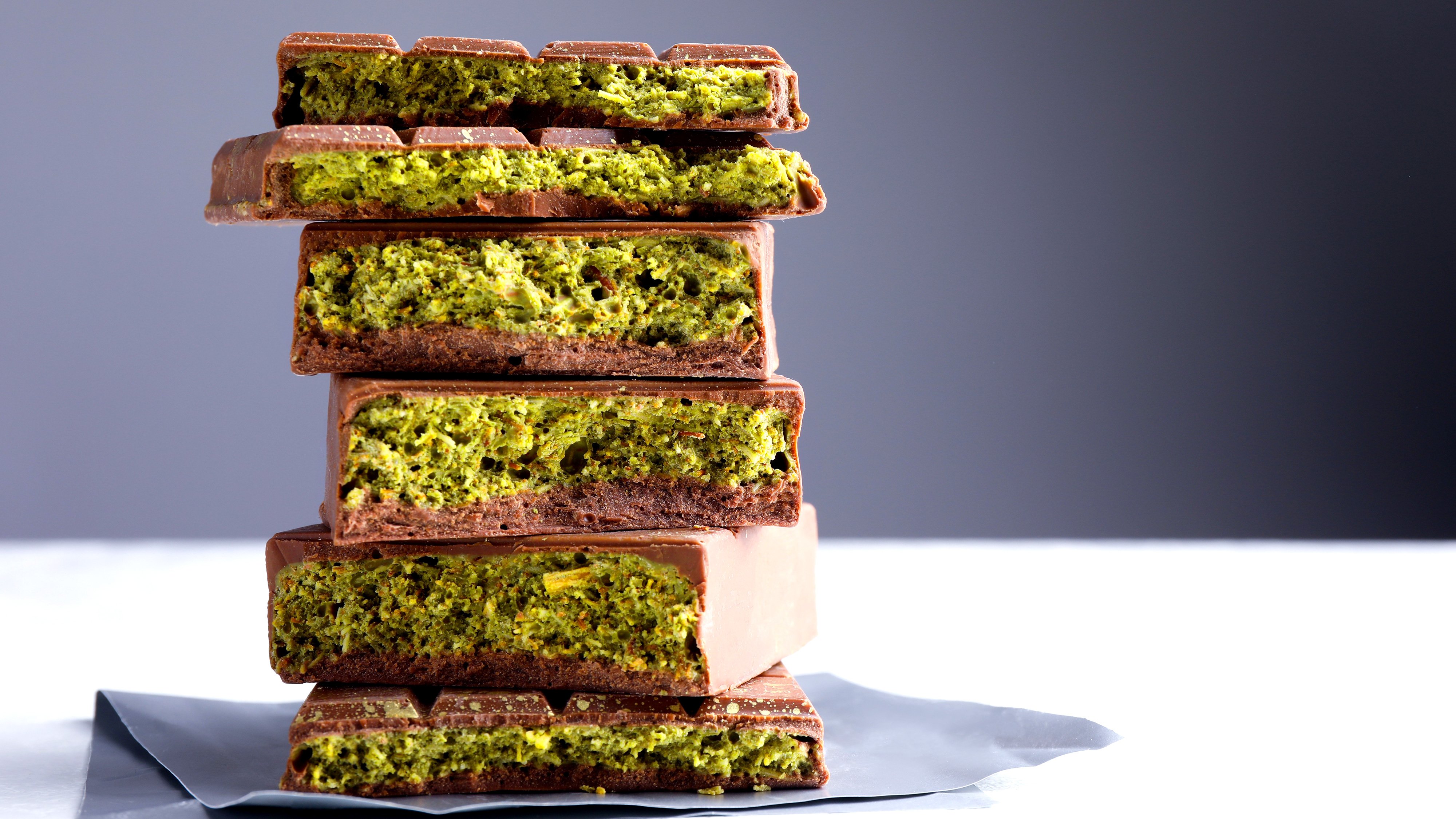 Fem staplade chokladbitar, där varje bit har en synlig grön pistagefyllning inuti.
