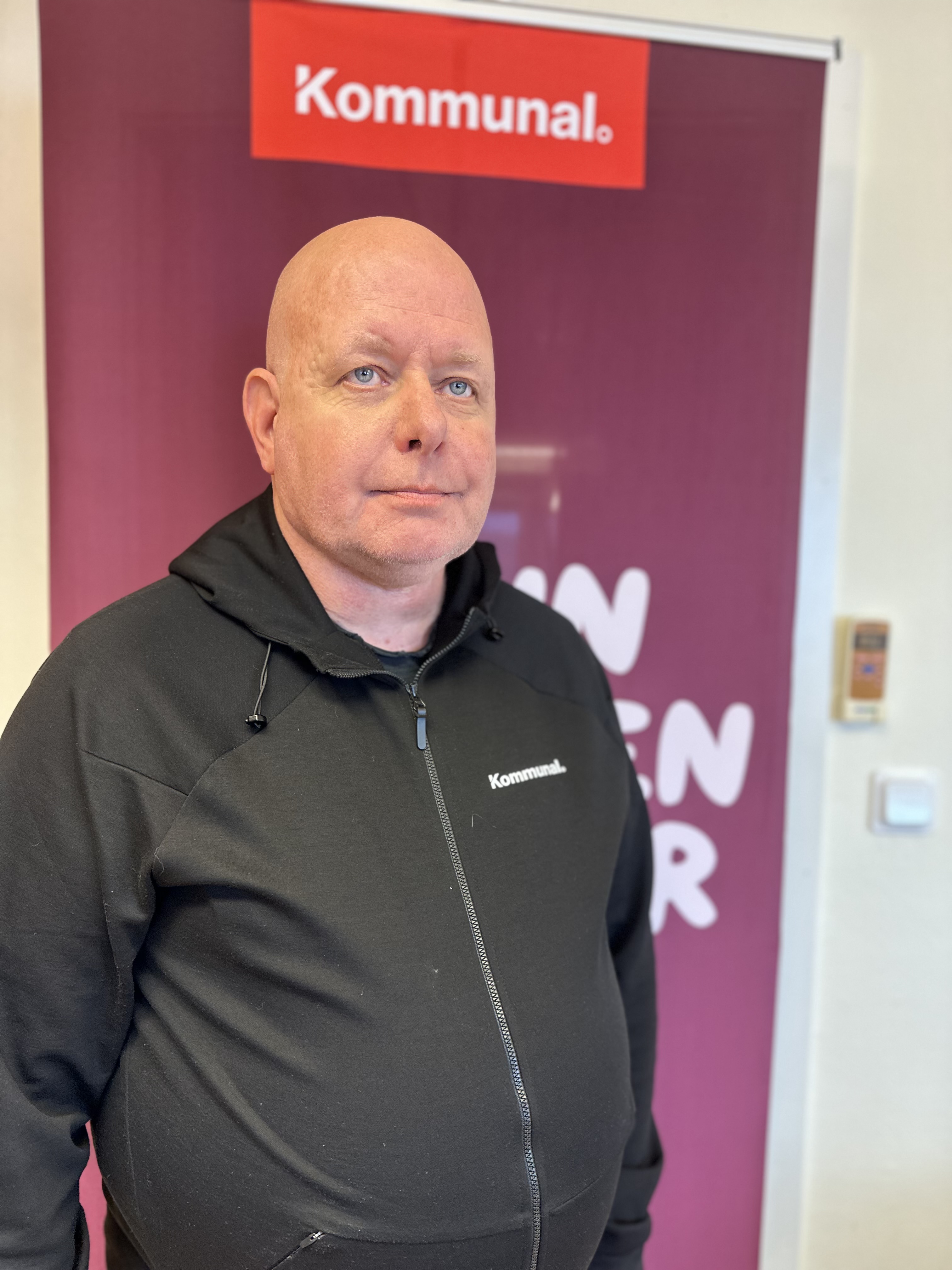 Anders Ejdemark framför en poster med Kommunals logga.