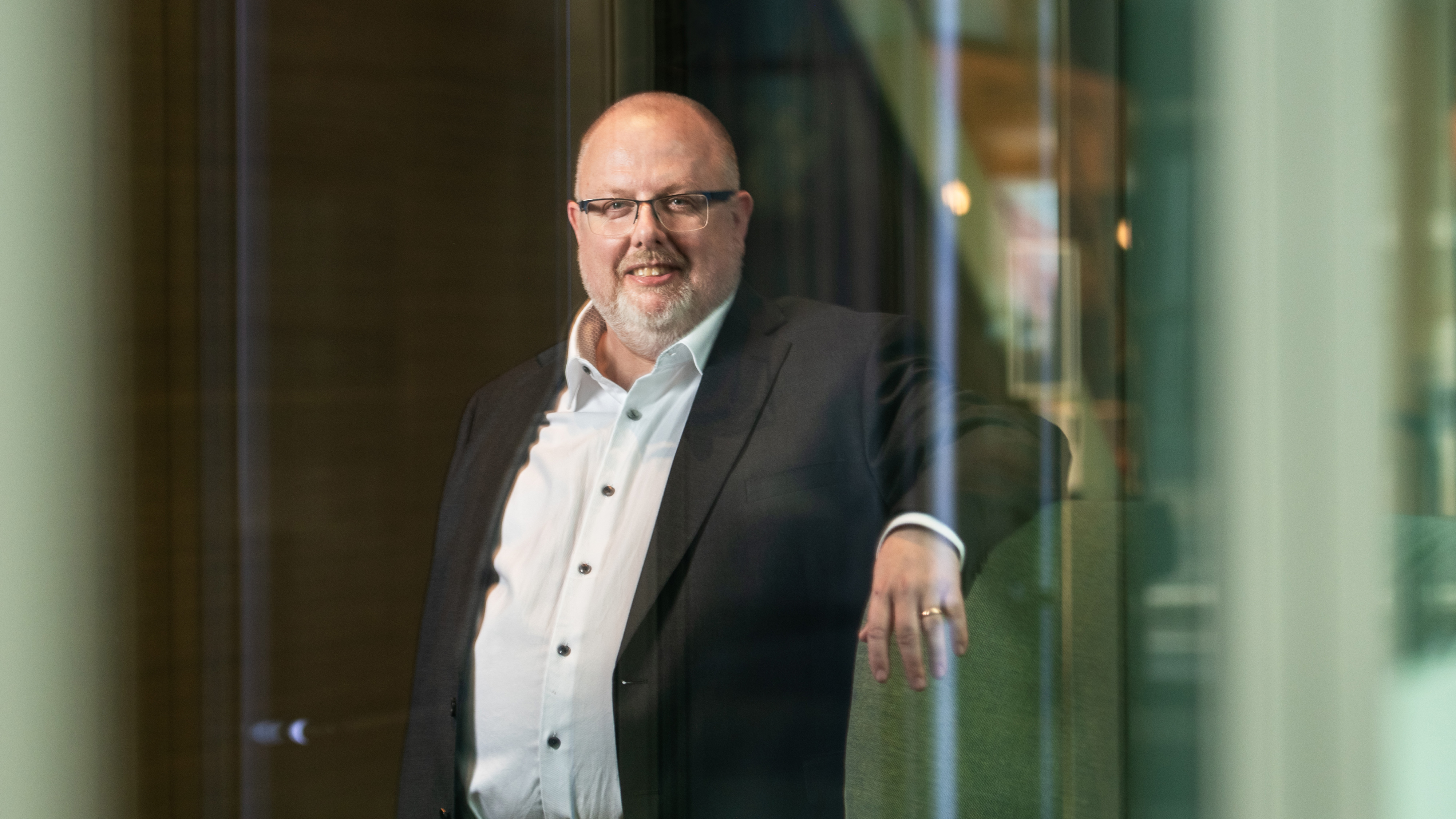 Lemmy Mauritzon iklädd kostym står vid en glasdörr.