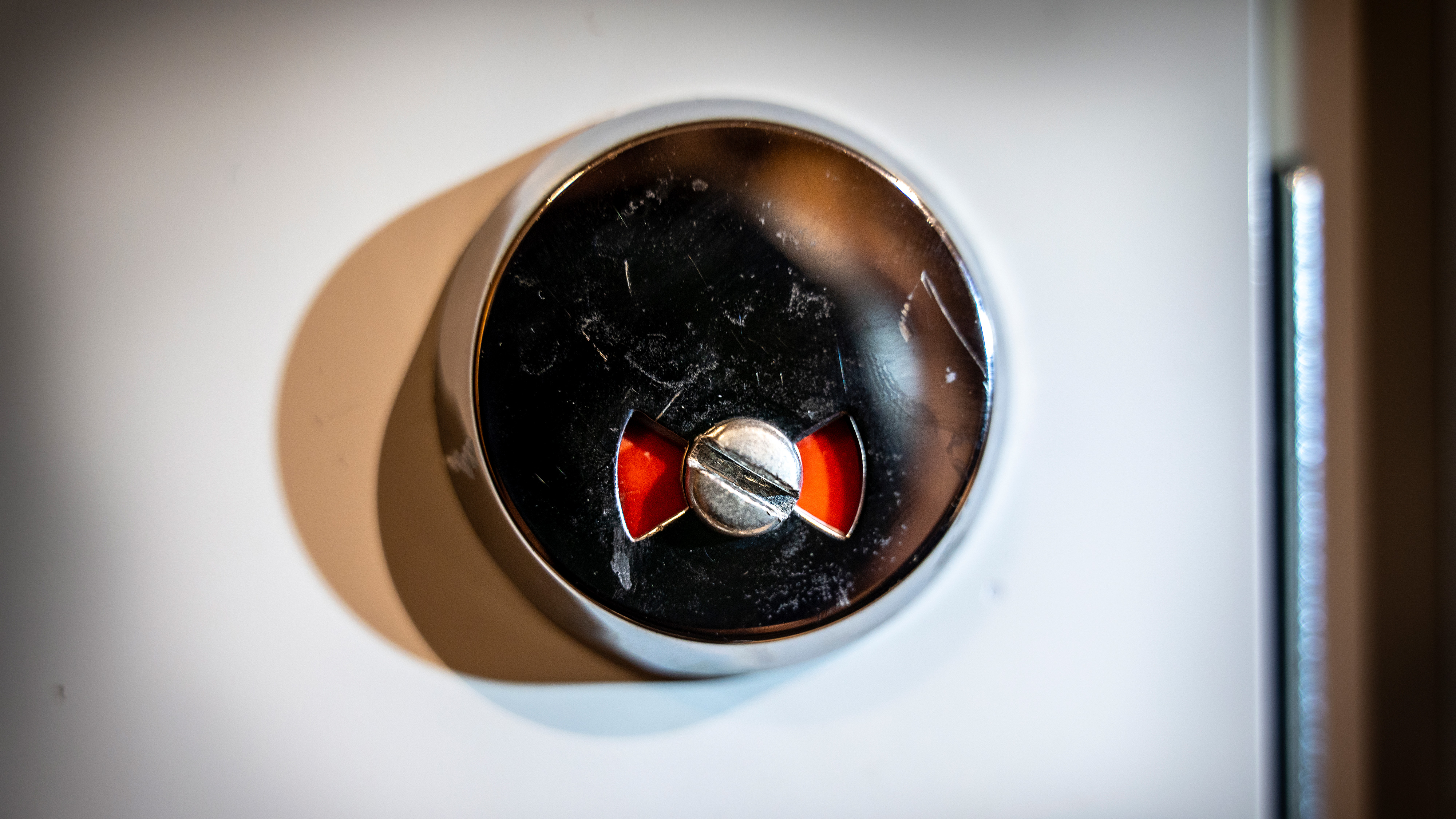 Närbild av en metallindikator som visar röda varningssektioner, troligen del av en mekanisk eller elektrisk apparat.