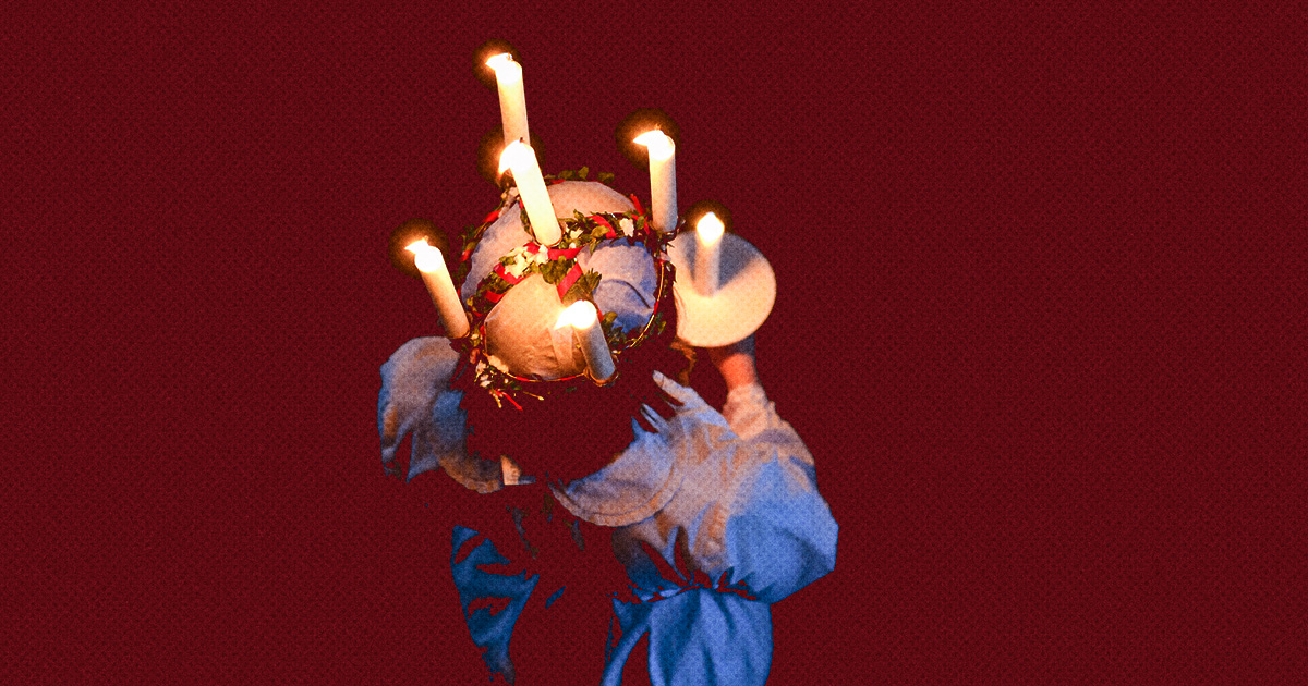 En person i vit dräkt och en krans med tända ljus på huvudet håller en tallrik, sedd bakifrån mot röd bakgrund.