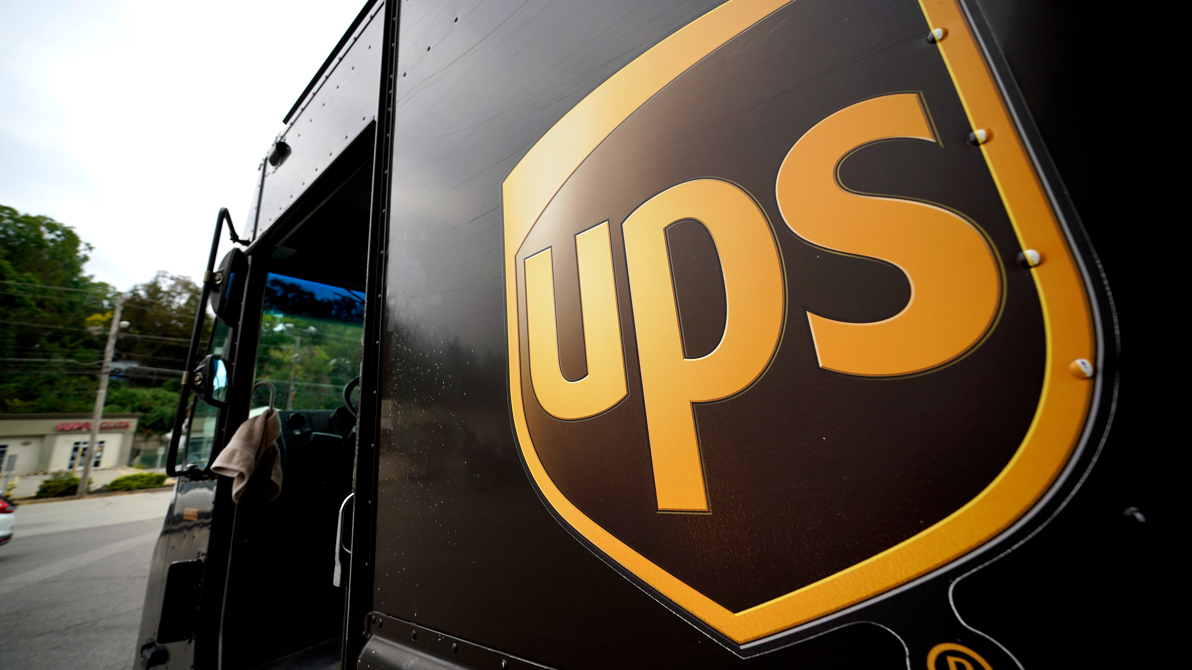 Närbild på en UPS-lastbil med UPS-logotypen på sidan och förardörren öppen.