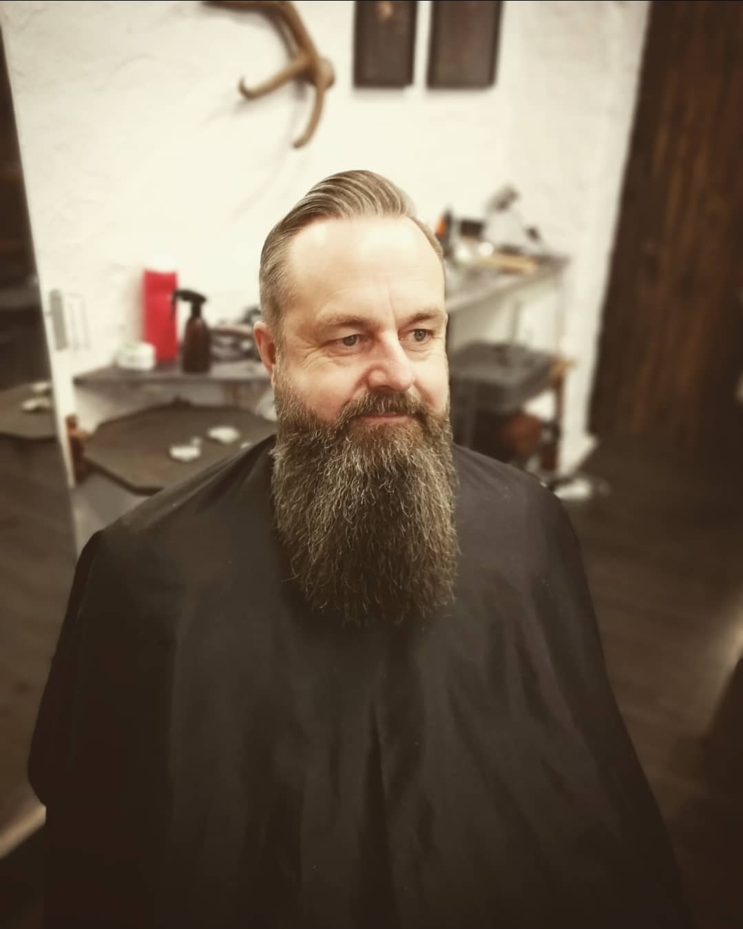 En man sitter i en barberarstol med ett långt skägg.