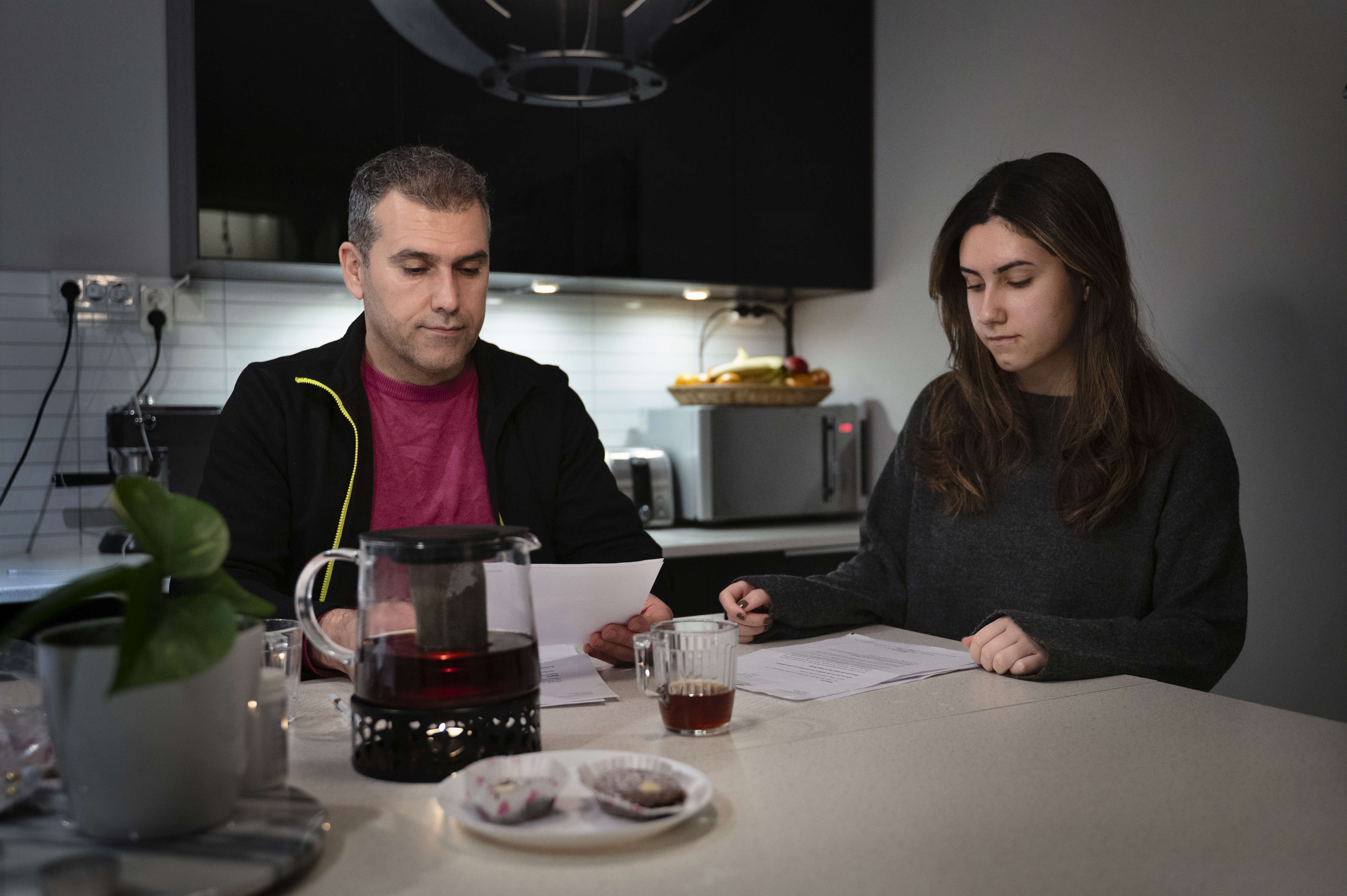 Zana Rafat och dottern Dalya Jaf sitter vid en köksbänk och går igenom dokument. En tekanna, fika står framme.