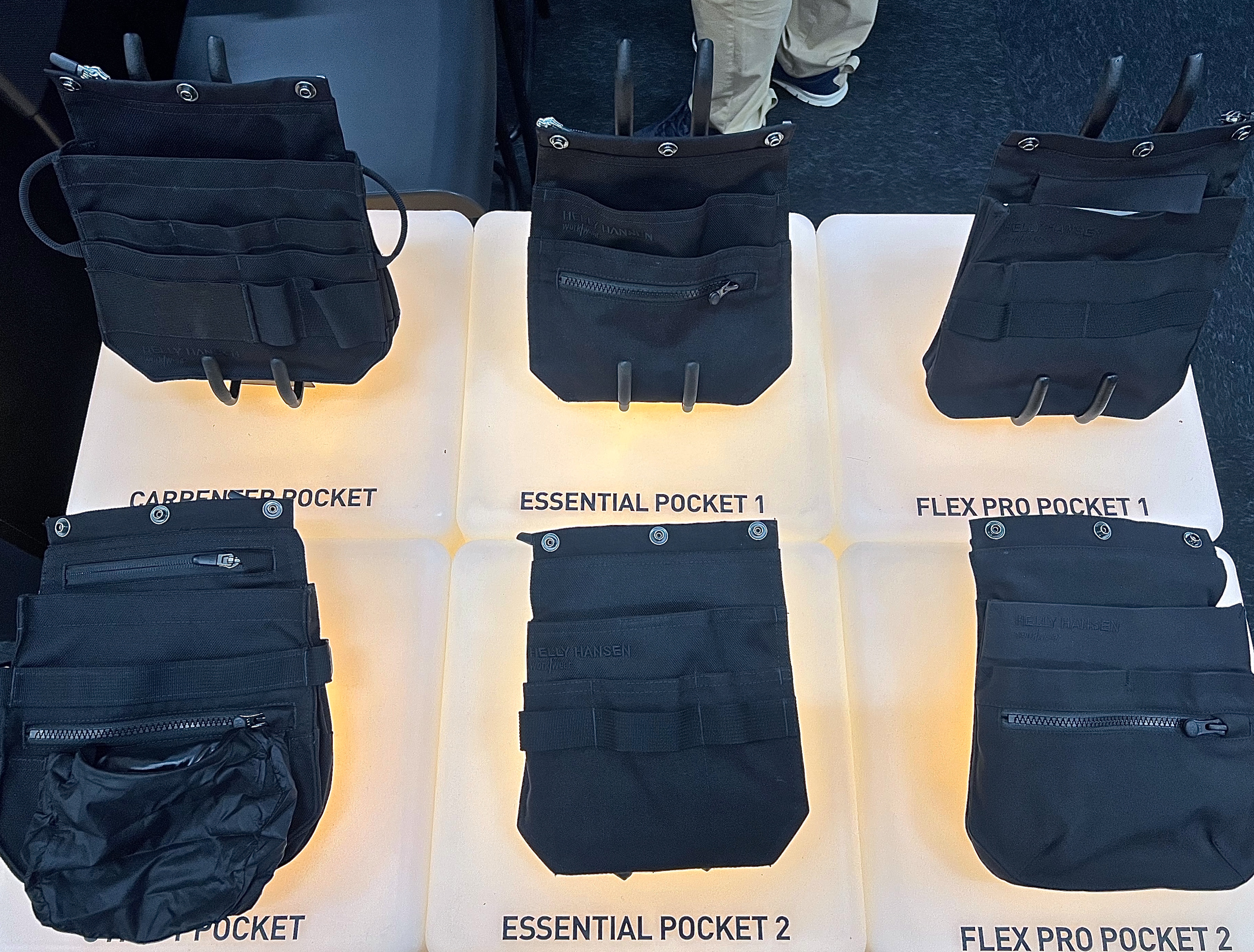 Sex svarta verktygsfickor märkta som "Carpenter Pocket 1", "Essential Pocket 1", "Flex Pro Pocket 1" på ett rutnät med upplysta baser.