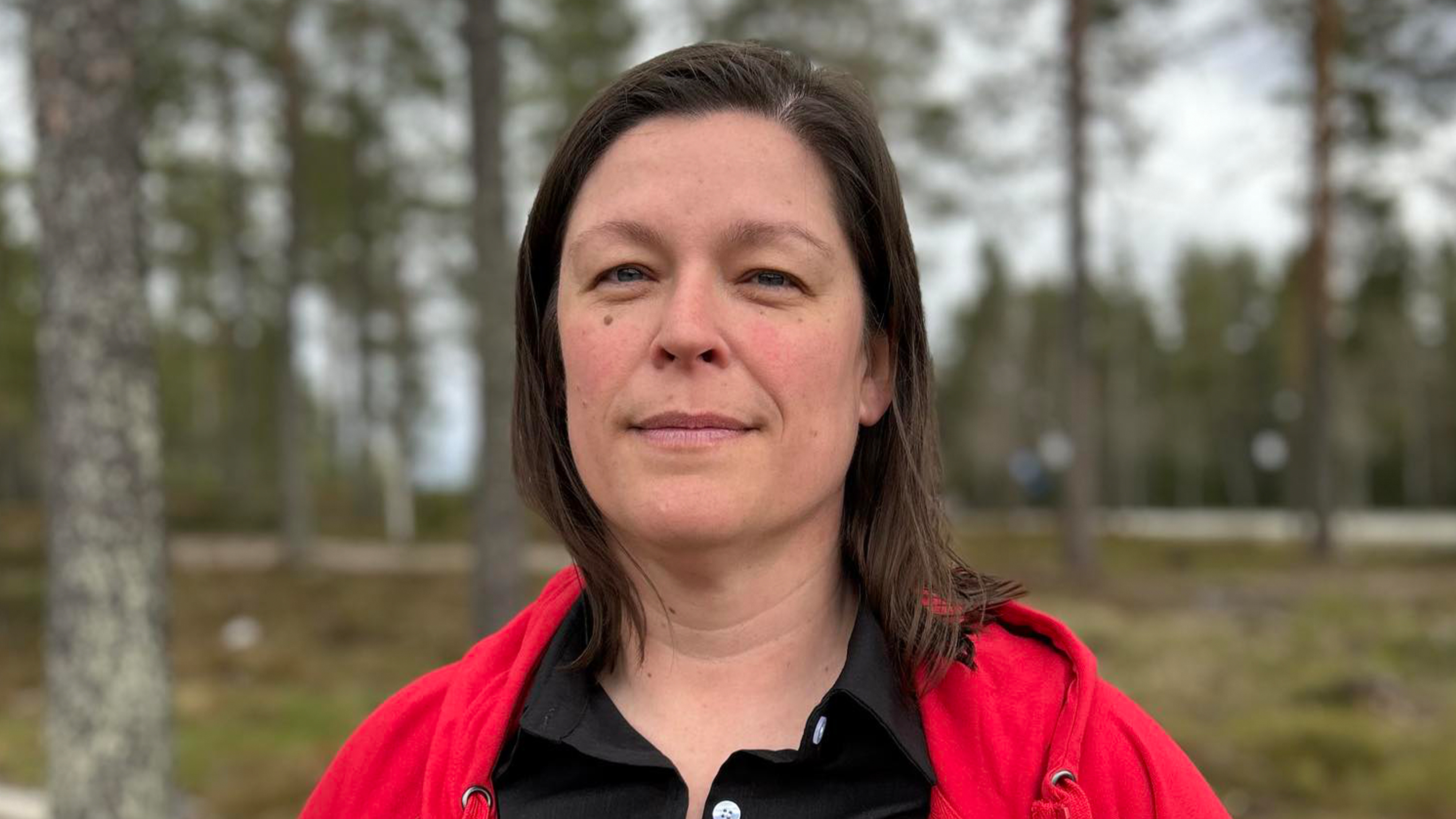 Kvinna med mörkt pagelångt hår tittar i kameran.