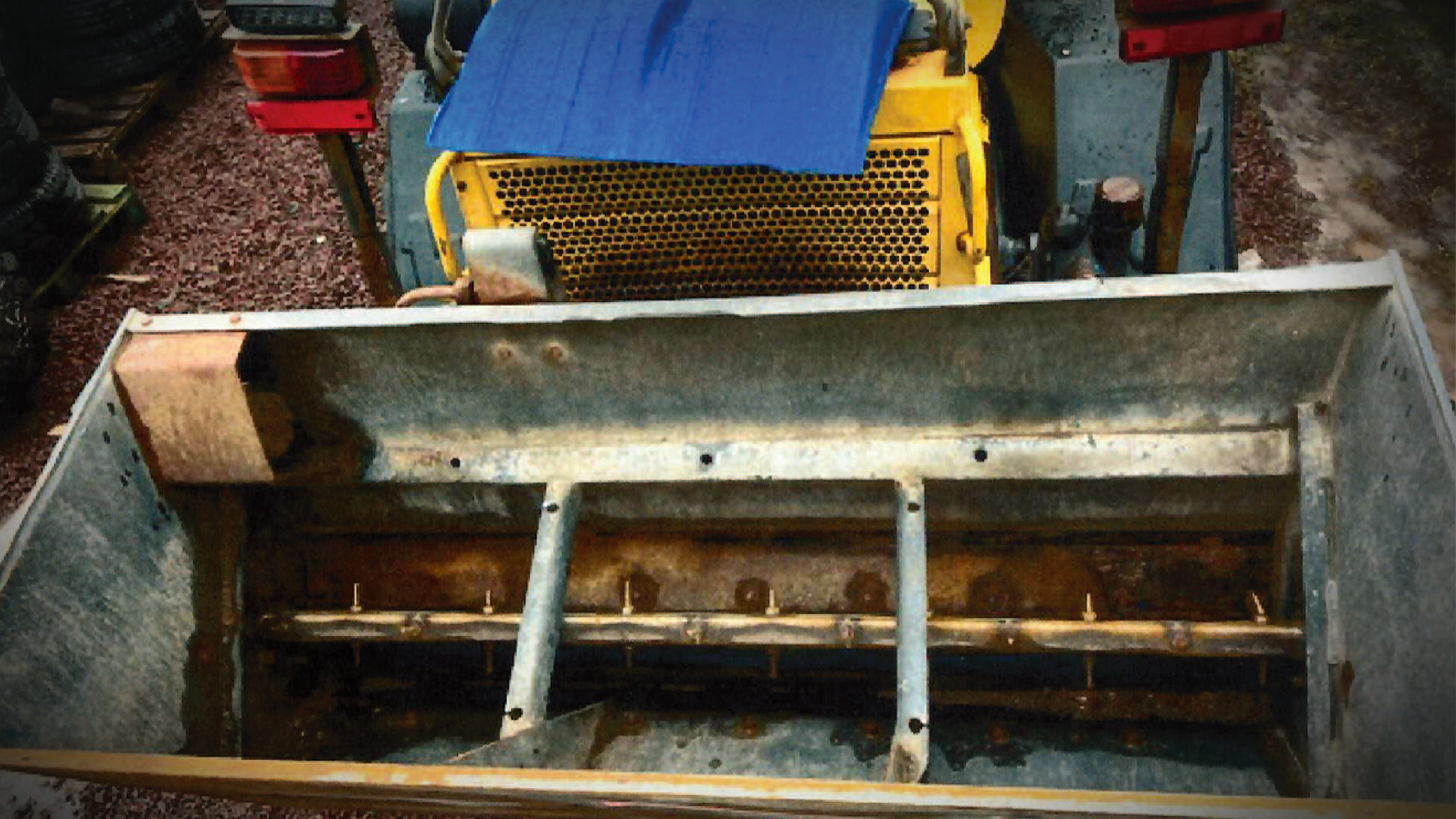 Närbild på en lantbruksmaskin med metalldel för roterande pinnar och ett galleri i gult synligt i bakgrunden.