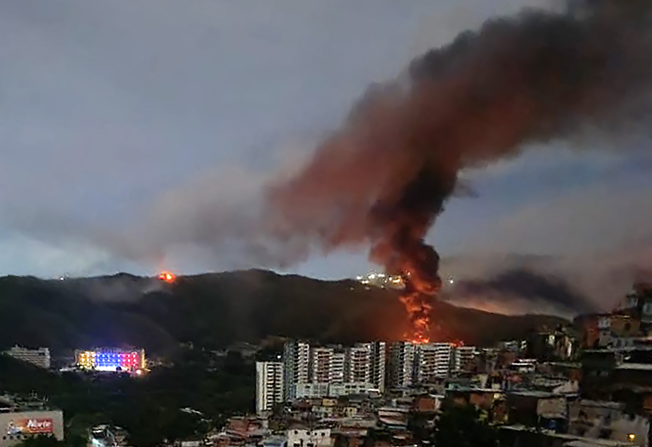 Brand vid Fuerte Tiuna, Venezuelas största militärkomplex, syns på avstånd efter en serie explosioner i Caracas den 3 januari 2026. USA:s militär låg bakom en rad angrepp mot Venezuelas huvudstad Caracas på lördagen, rapporterade amerikanska medier.