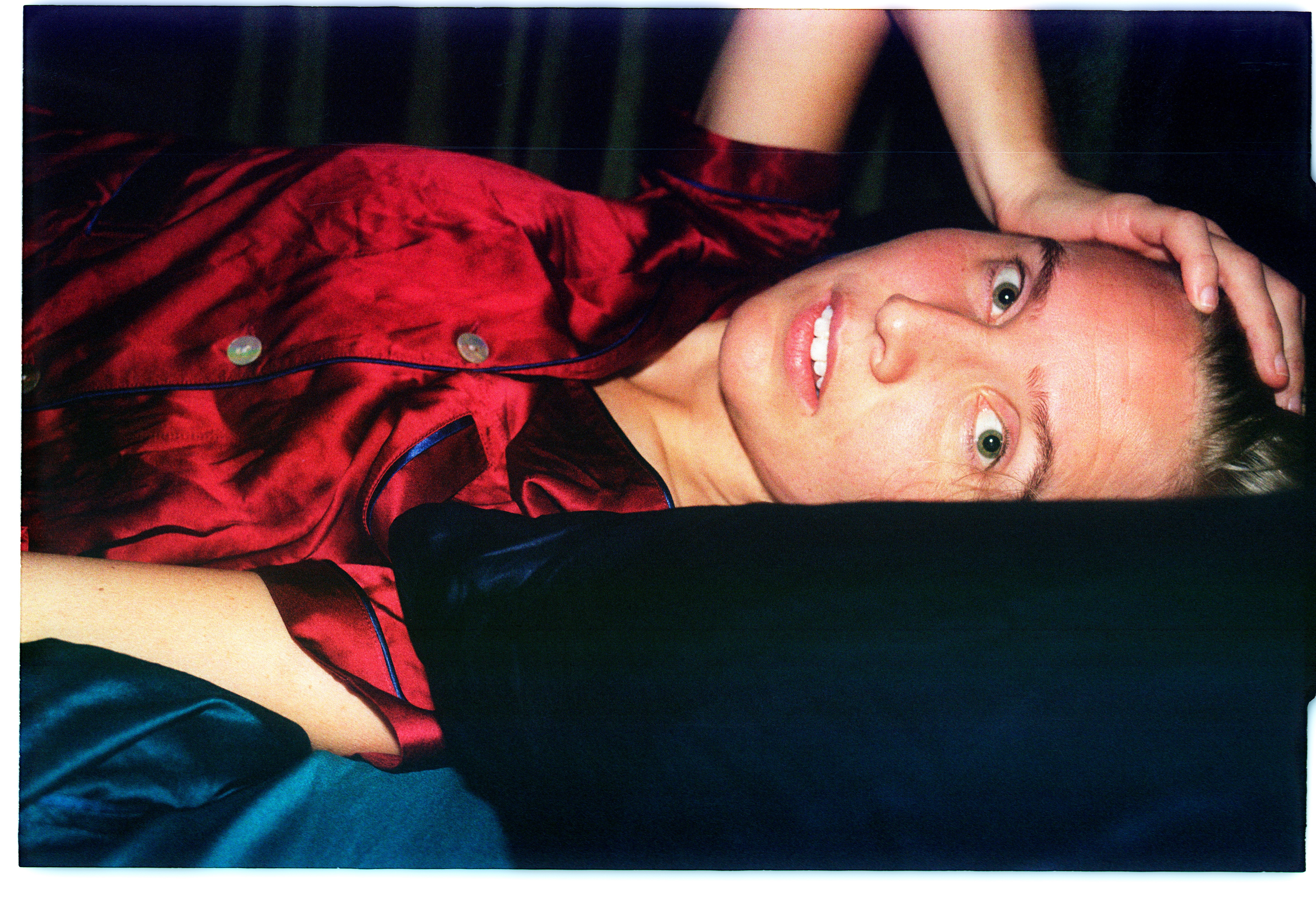 Amanda Romare ligger på en säng i röd tröja.