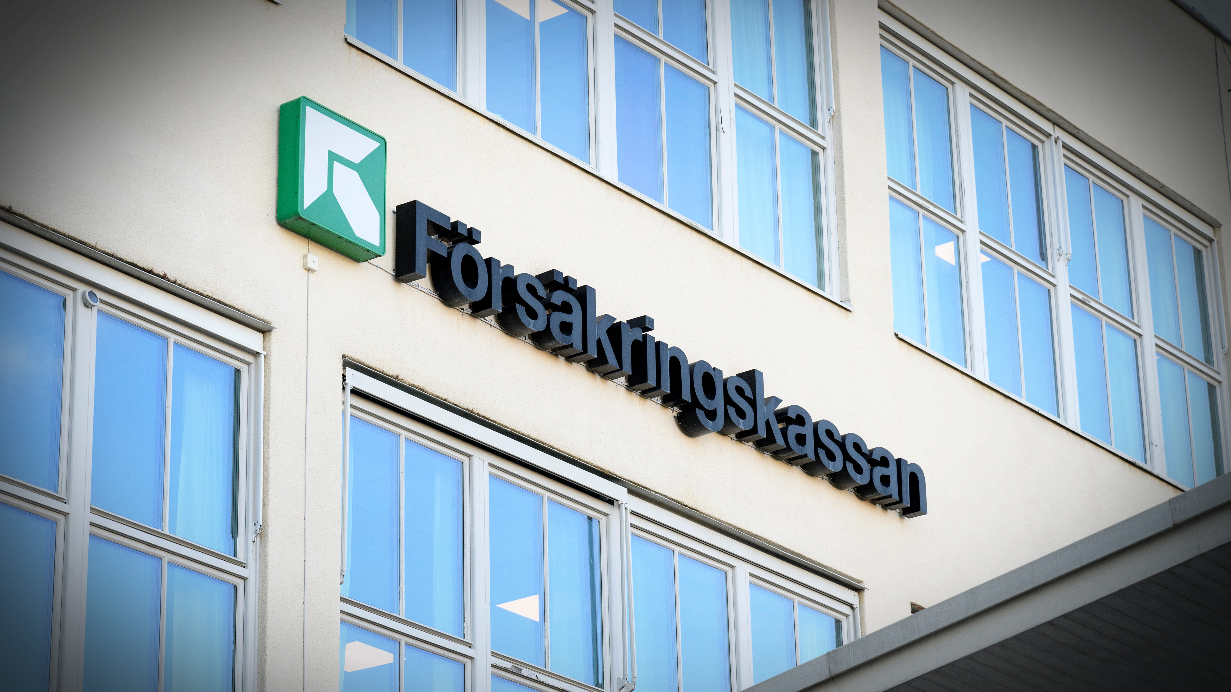 Skylt där det står Försäkringskassan och mydighetens logotyp på en husfasad.