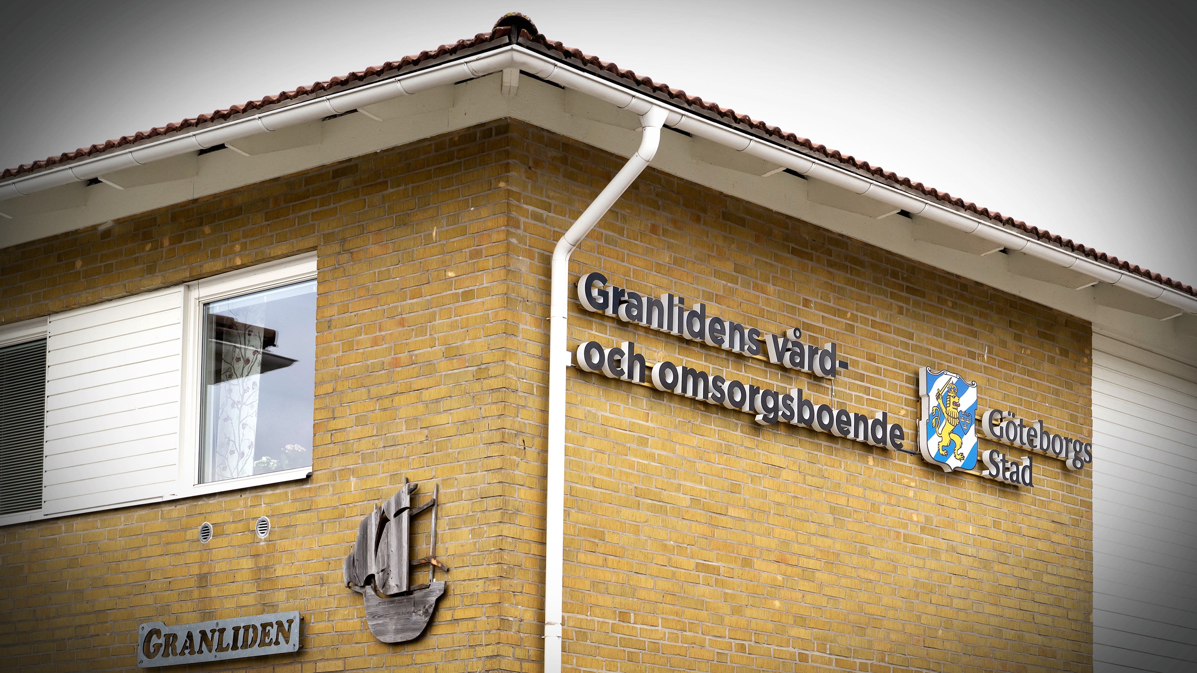 En byggnad i tegel med en skylt där det står "Granlidens vård- och omsorgsboende Göteborgs stad" och ett träskepp på väggen.