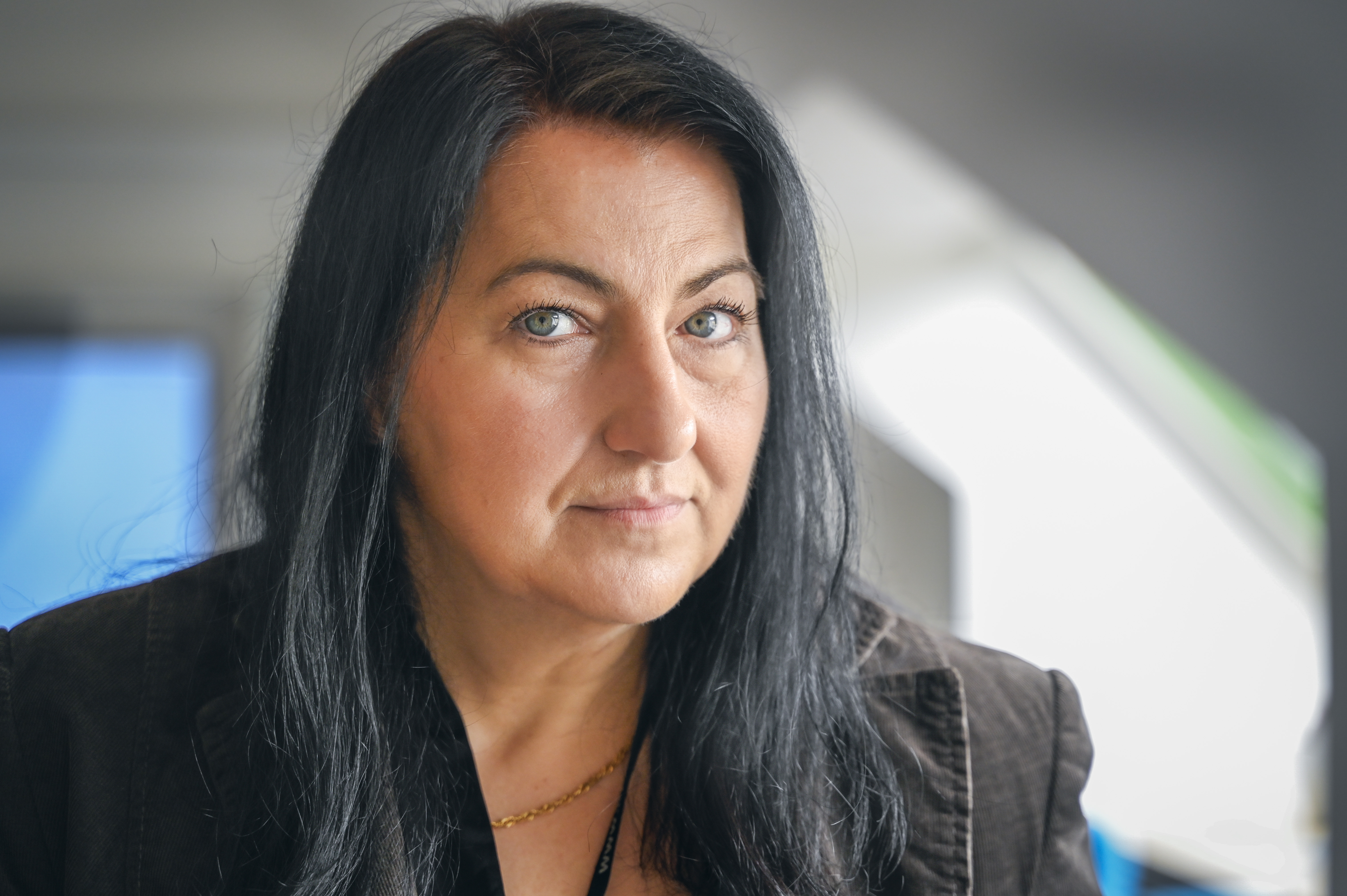 En kvinna med långt mörkt hår tittar rakt mot kameran inomhus.